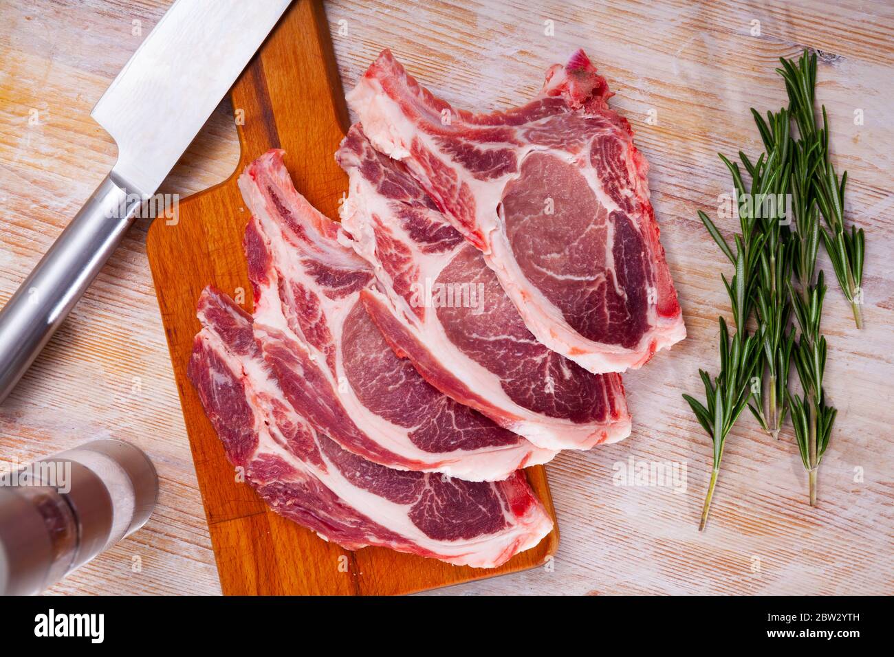 Image of raw pork's  chops and rosemary on wooden surface, nobody Stock Photo