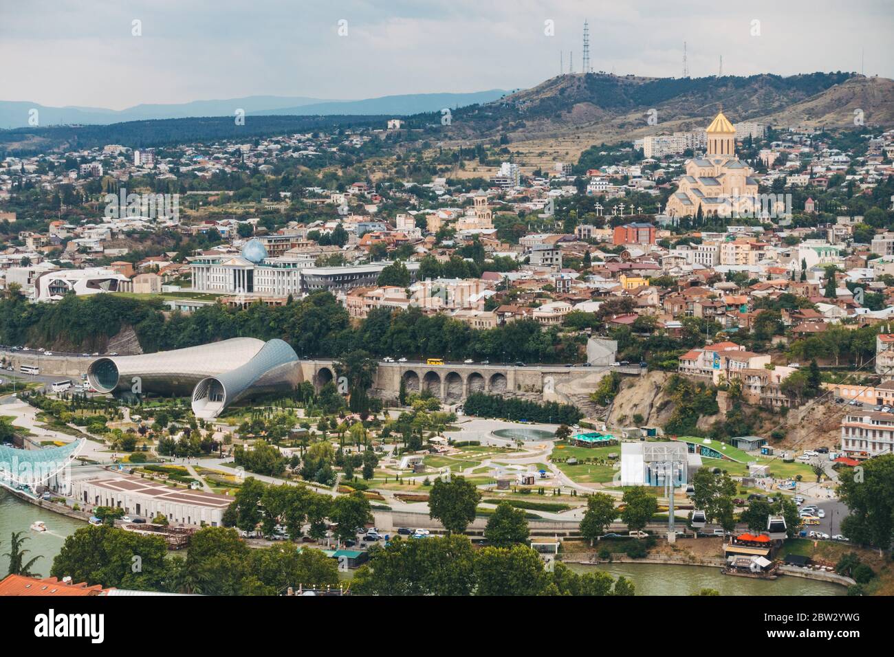 Looking out over the city of Tbilisi, Georgia from the Botanical Garden on the hilltop. The cylindrical metal structure is Tbilisi Music Theater Stock Photo