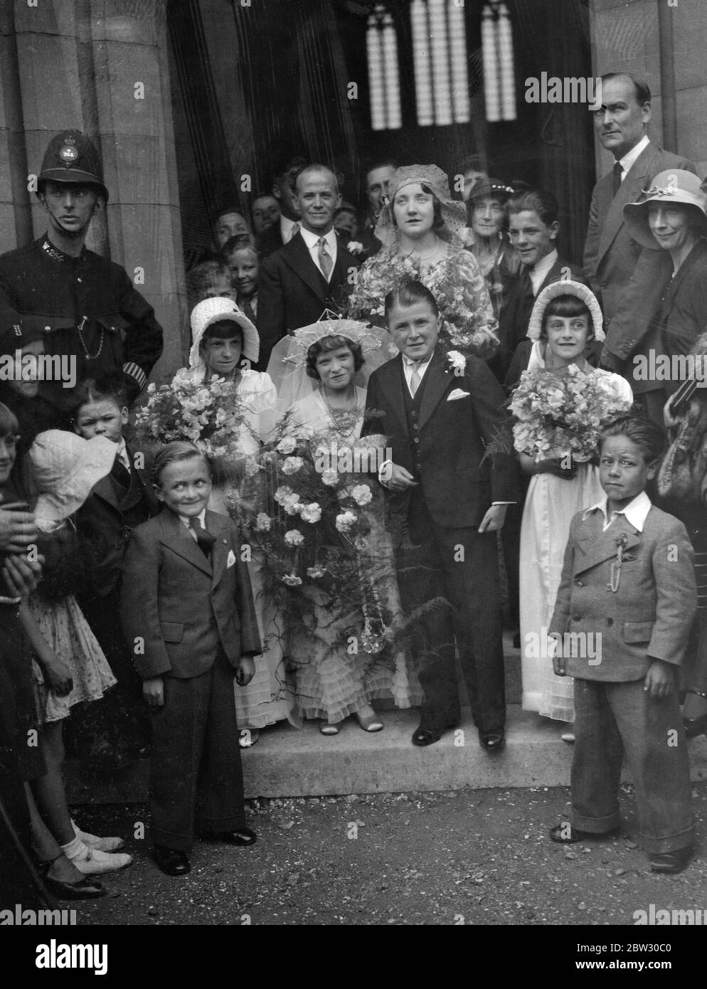 England ' s tiniest bride and groom marry at Mitcham . Miss Dorothy Kathleen Griffiths , who is only 3 feet 10 inches tall , and Mr Vivian Pascoe , who is two inches taller , both belonging to a midget circus troupe were married at St Barnabas Church , Mitcham , Surrey . The wedding was attended by members of the Theatrical Company with whom they are playing . The bride and groom with the bridal party at the wedding . 14 August 1932 Stock Photo