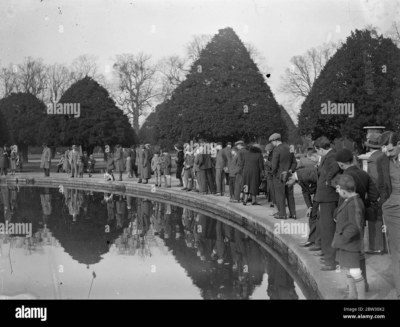 Sunday crowds at Hampton court . The brilliant sunshine of the first Sunday of spring brought out large numbers of visitors to Hampton Court Palace . Crowds at Hampton Court Palace beside the lily pond . 20 March 1932 . Stock Photo