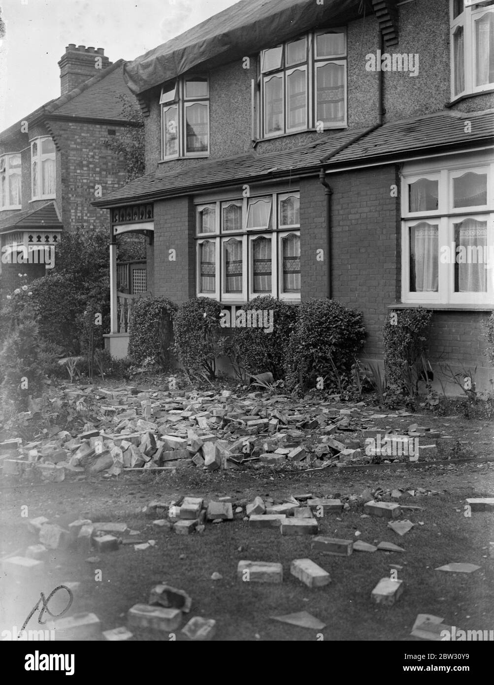 Houses damaged in great storm at Enfield . Two semi detached houses were struck and badly damaged by a thunderbolt during the great storm which broke over London . The greater part of the roof was torn away and pieces of furniture were scattered about and thrown on to the floor . Fireplaces were blown and water pipes burst . Mr Franck Higham with his wife and child were at tea when the thunderbolt came down the chimney , and had a narrow escape . Mr Frank Higham clearing away the debris from his garden after the havoc wrought by the storm . 23 July 1932 Stock Photo