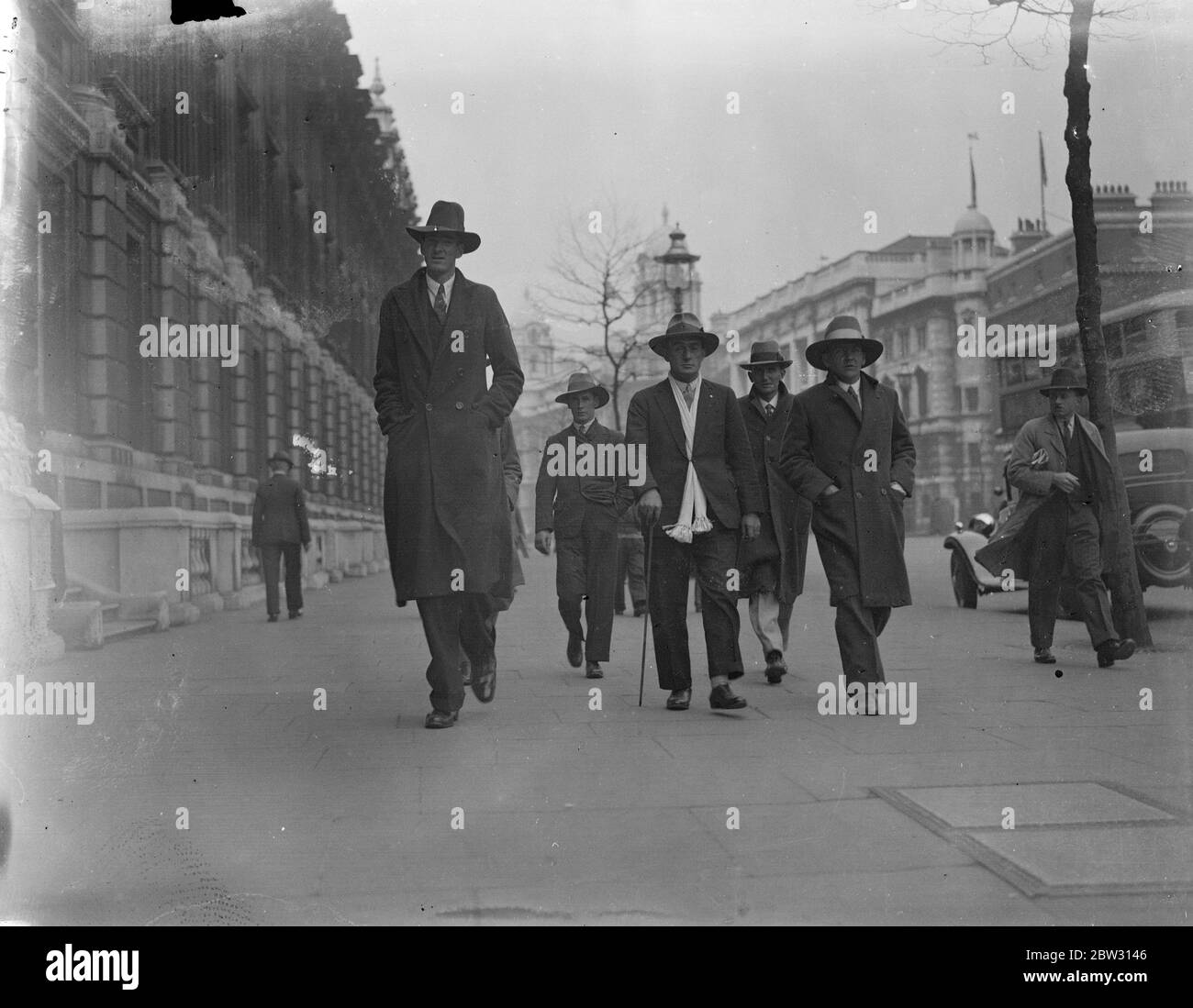 South African giant comes to London in search of work . Dennis Buffey , who is seven feet 11 inches tall , has arrived in London from South Africa , in search of work . Dennis Buffey walking down Whitehall , London with some of his friends . 25 April 1932 . Stock Photo