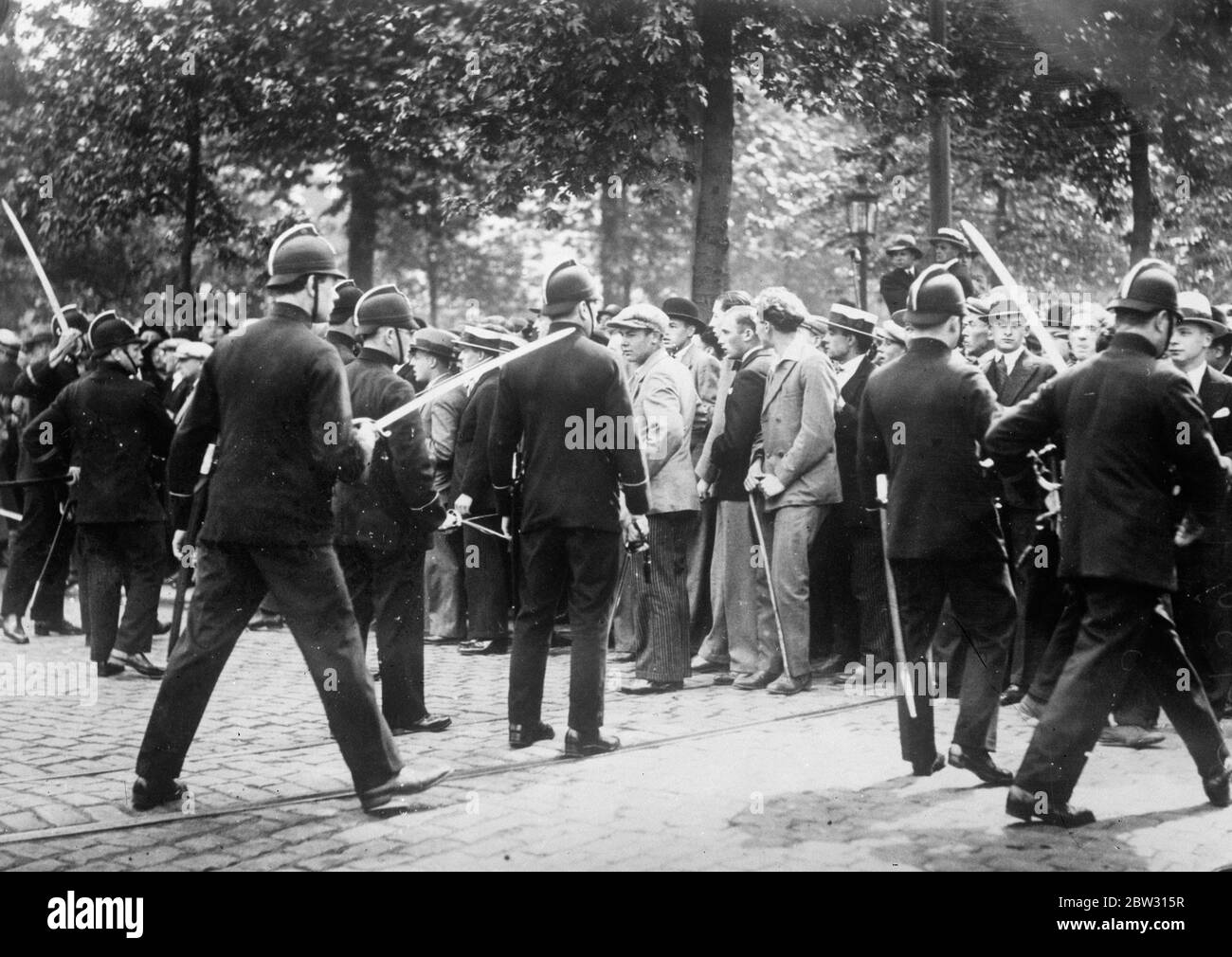Police drive rioters from Berlin streets with waterbuns . Employing powerful water guns , mounted on armoured lorries , police drove rioting Nazis and Communists from the streets . Hundreds of police in cars and trucks were rushed to the suburbs of Berlin where the rioting took place . Policeman use batons to keep crowds back . 27 June 1932 Stock Photo