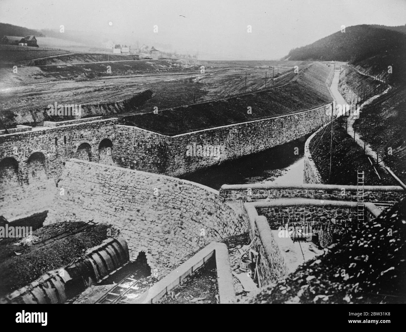 Germany building the world 's largest dam . Work on what is going to be the world 's largest artificial dam is in progress in the Surpo Valley in Westphalia . The wall of the dam will be eighty feet high and more their eight hundred feet long . A view of the work in progress . 4 May 1932 Stock Photo