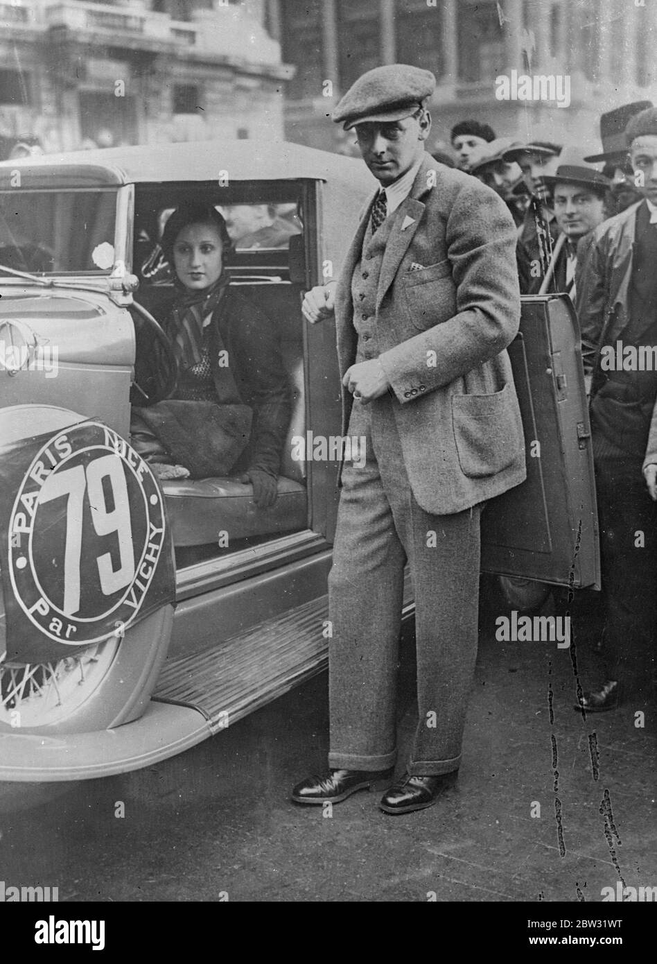 Prince Nicholas of Romania and bride compete in Paris to Nice motor race . Unusual interest was lent to the eleventh annual Paris to Nice automobile race via Vichy as Prince Nicholas of Romania and his bride were among the competitors at the starting line . The whole world has been interested in the love romance of Prince Nicholas and his bride , who was formerly the wife of Romanian officer . King CArrol banned the marriage and Prince Nicholas and his bride are living in exile and have refused to return Romania until the marriage is recognised . Prince Nicholas and his bride justt before the Stock Photo