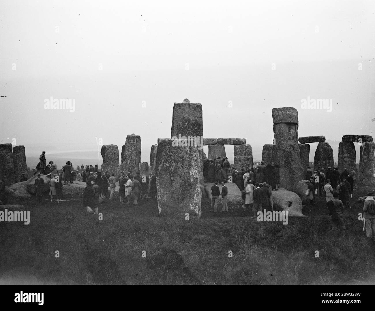 Crowd watches the sun rise at Stonehenge on longest day of the year . A crowd of people gathered at Stonehenge motoring in from miles around , to watch the sun rise at Stonehenge at dawn on June 21 , the longest day of the year . Ancient superstition has it that as the first rays of the rising sun touch the altar , which occurs only at the summer solstice , the blood of former human sacrifices may be seen on the stones . A view showing the crowd at Stonehenge at dawn to watch the sun rise . 21 June 1932 Stock Photo