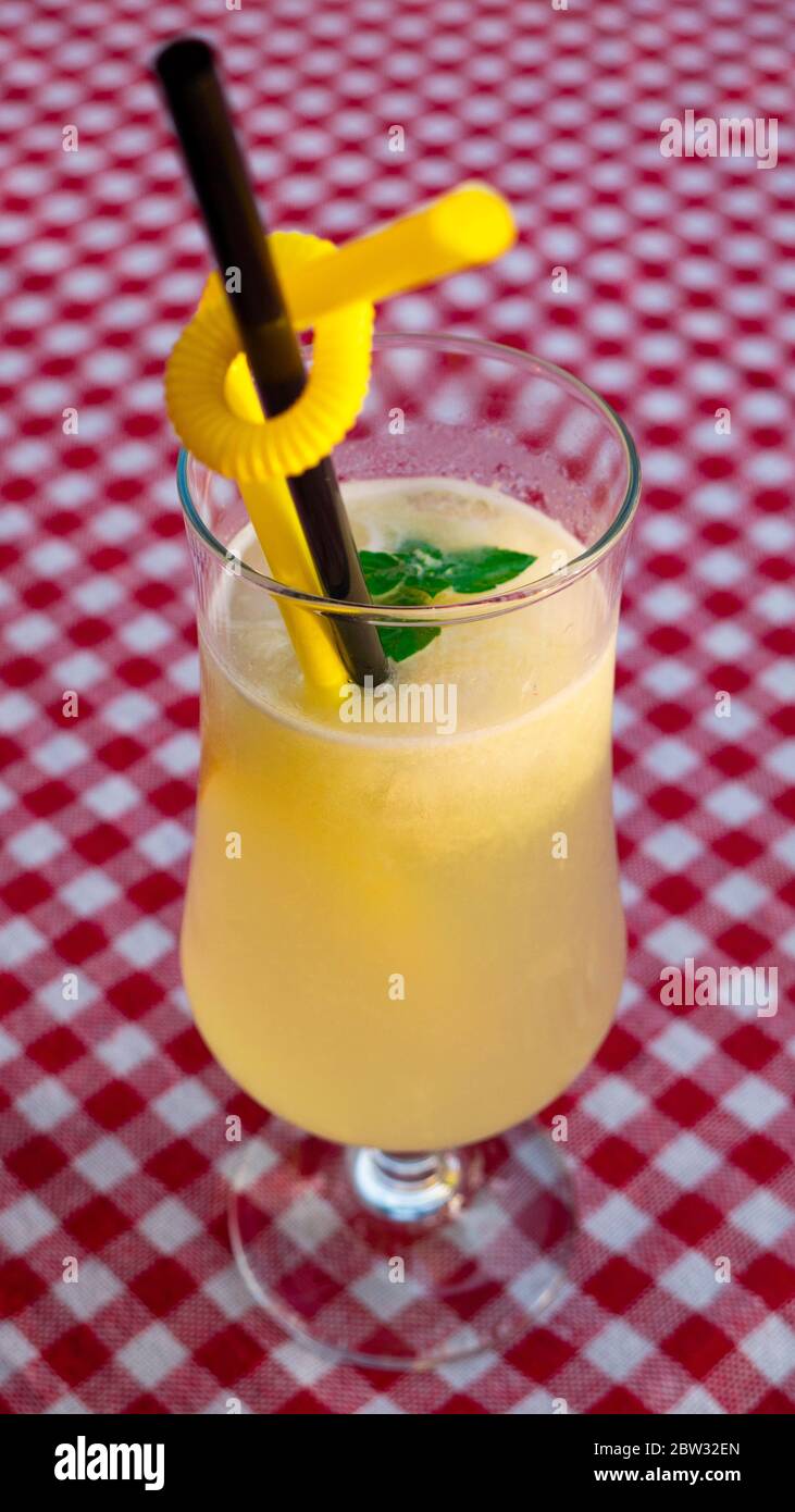 A glass of lemonade on a checkered red-and-white tablecloth. Stock Photo