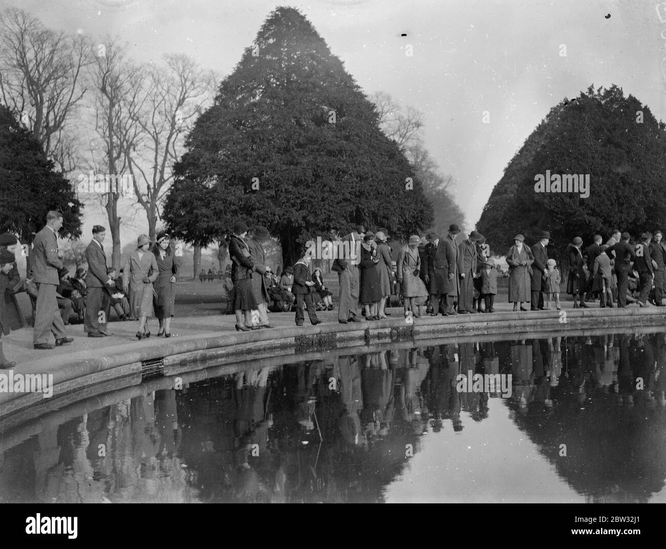 Sunday crowds at Hampton court . The brilliant sunshine of the first Sunday of spring brought out large numbers of visitors to Hampton Court Palace . Crowds at Hampton Court Palace beside the lily pond . 20 March 1932 . Stock Photo