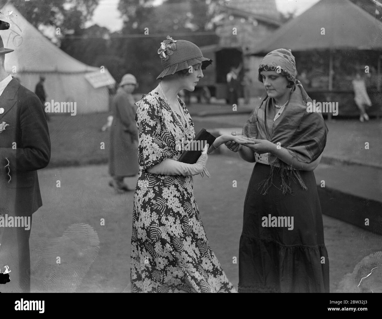 Lady Diana Cooper has her fortune told . A palmist telling the fortune of Lady Diana Cooper at the great Country Fair at the Royal Botanical Gardens , Regents Park , London , which she opened . 30 July 1932 Stock Photo
