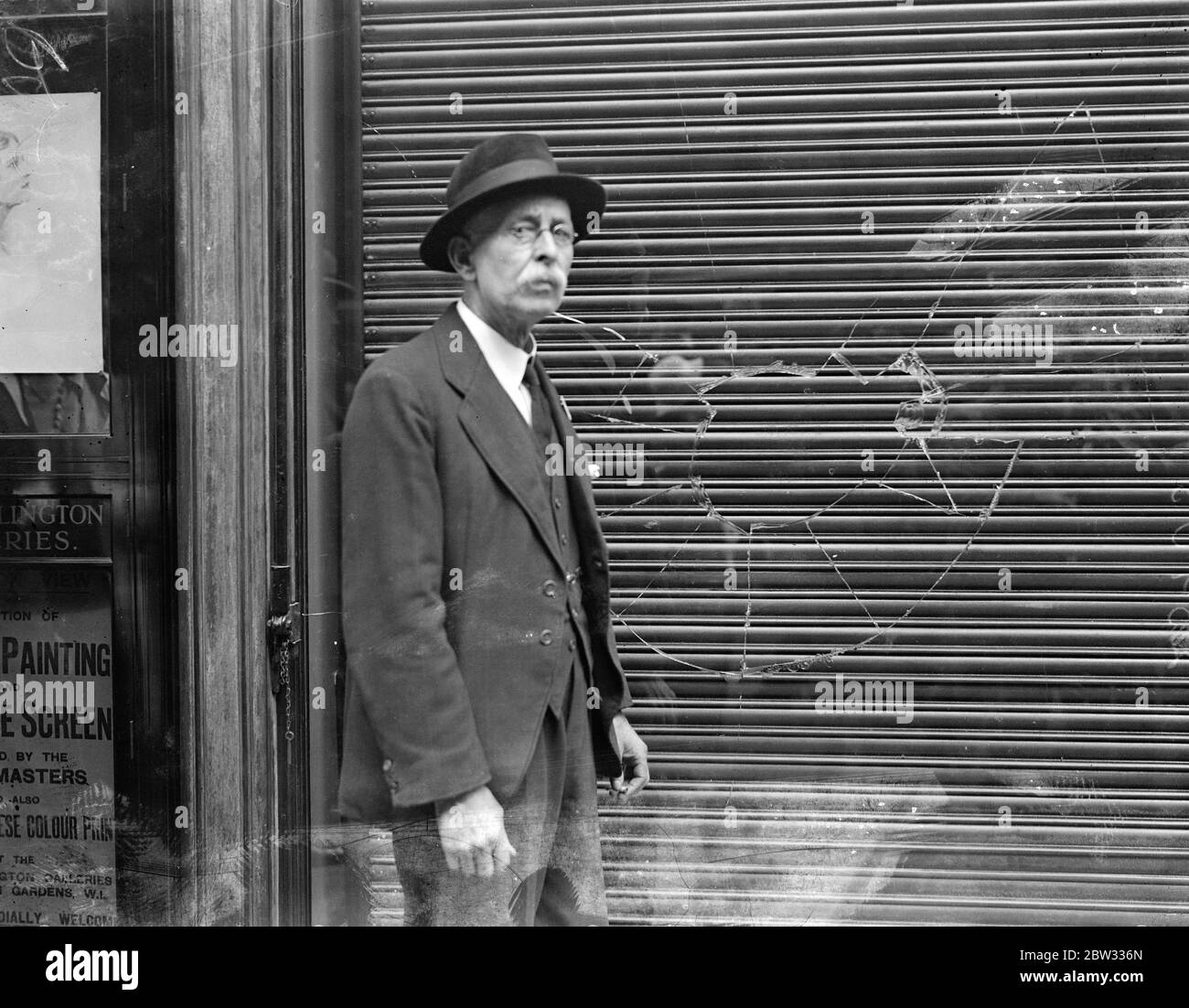 New anti smash and grab raid invention tested at Piccadilly jewellers . A new anti smash and grab raid device , invented by Mr William Samuel , was tested out at the shop of Mr E Sinclair , jewellers , in Burlington Gardens , Piccadilly , London . As the window is smashed a shutter comes down to protect the interior . Mr William Samuel beside the shuttered window after a test raid had been carried out . 24 June 1932 Stock Photo