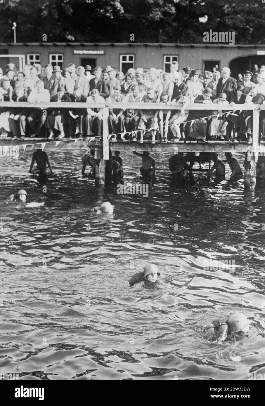 Germany army holds water festival . Soldiers in full kit swimming in a race during the German Army ' s water festival at Spandau , Germany , which was watched by large crowds . 2 August 1932 Stock Photo