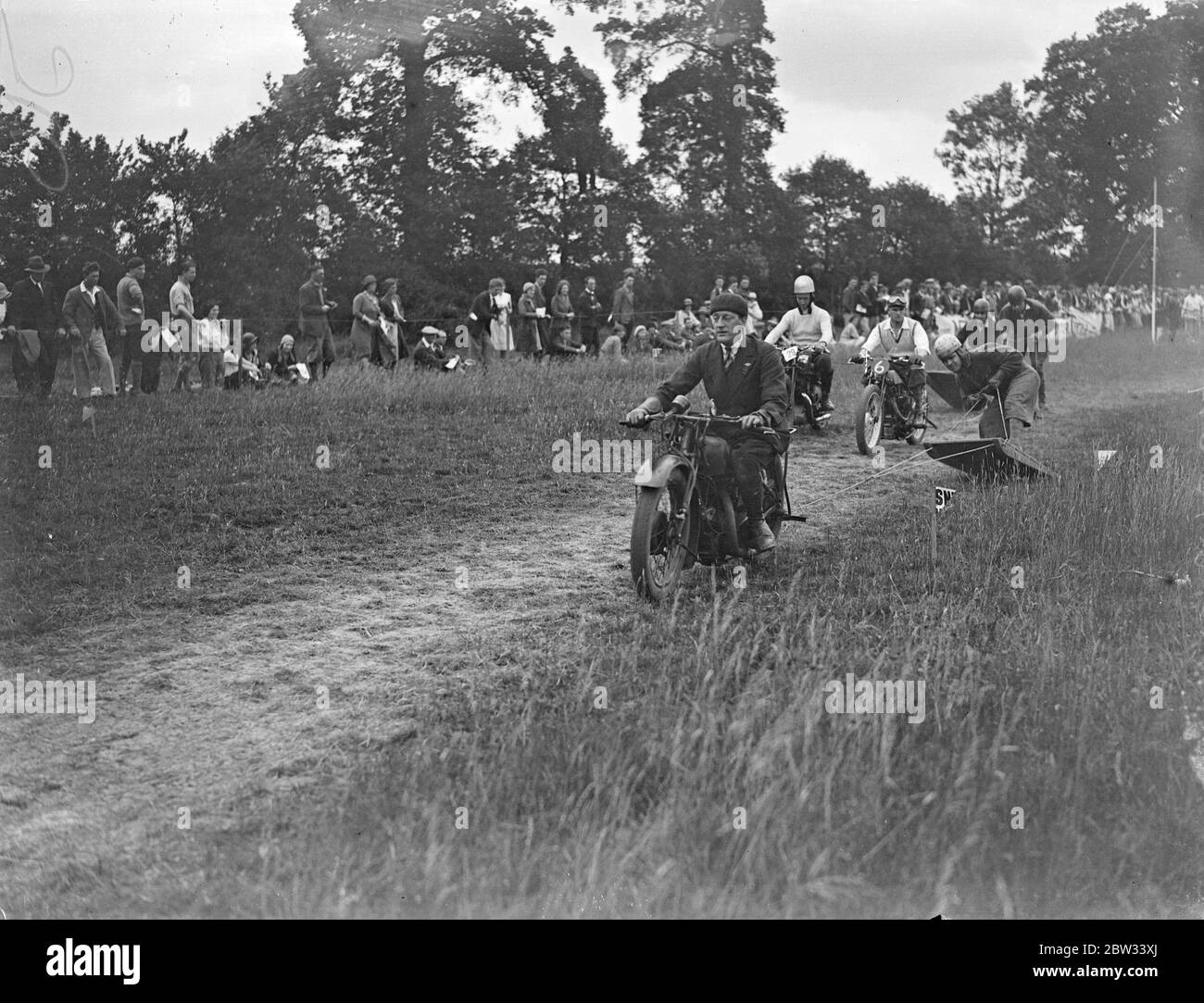 Surf board riding behind motorcycles over the ground , Britains latest sport . Surf board riding behind motorcycles over a grass track is the latest sport in Britain . The surf board racing is being increasingly staged at sports meeting throughout the country and provides a great thrill for the spectators and the riders alike as the motorcycles speed over the ground drawing their riders . Spills are frequent . A girl surf board rider winning a race at the Wembley Speedway SPorts motor club meeting at Hillingdon , near Uxbridge . 26 June 1932 Stock Photo