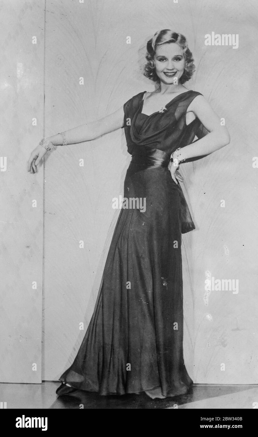 Draped neckline for evening wear . Beautiful Adrrenne Lore wearing a gown of double chiffon in royal blue , with a draped neckline and a wide sash of matching satin . 16 April 1932 . Stock Photo
