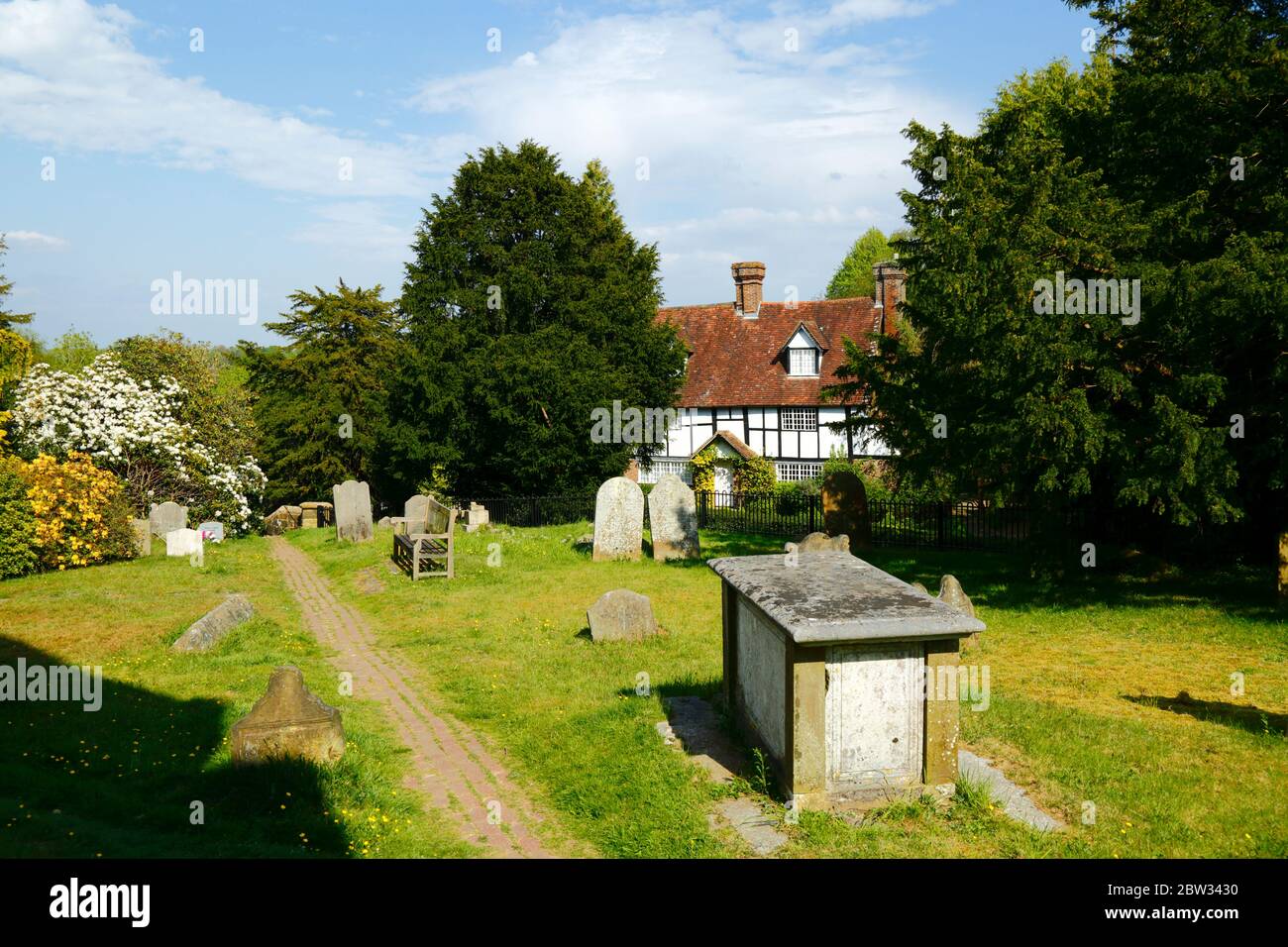 Quaint traditional white timber framed house and gravestones in churchyard of parish church, Speldhurst, Kent, England Stock Photo