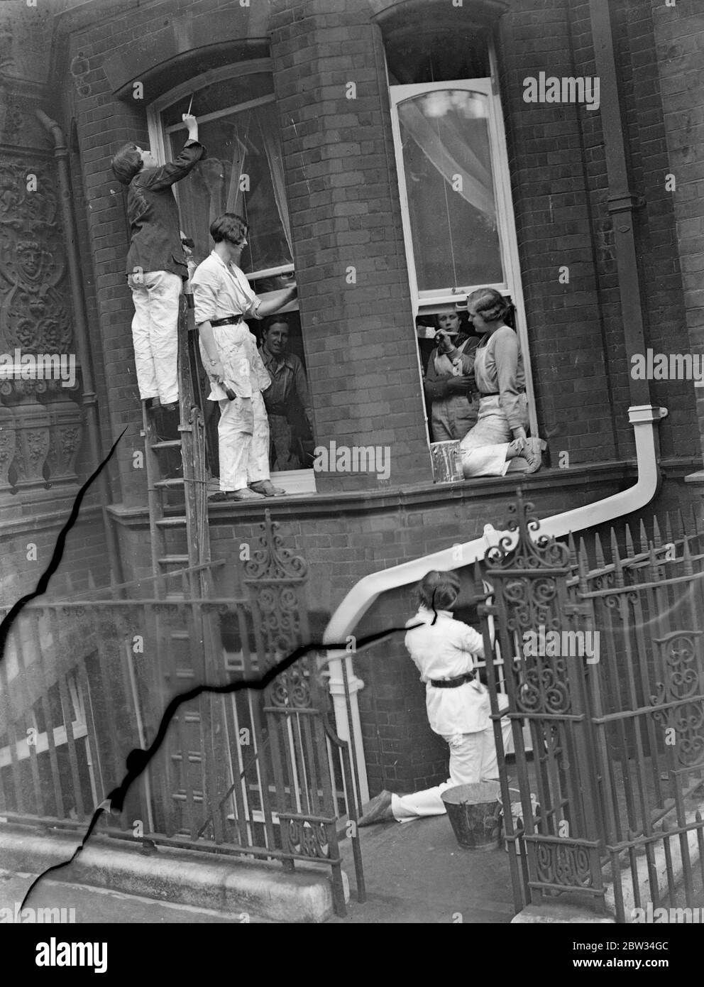 Women decorate a London house in Chelsea . Miss Elisabeth McNabb , daughter of Surgeon Rear Admiral , Sir Daniel McNabb , with Miss Margaret Dodds , and her pupils are decorating the outside of a house in Dreycot Place , Chelsea , London . The women decorators do the entire work from the roof downwards . Miss Elisabeth McNabb ( left at top ) with her pupils decorating the outside of a house in Chelsea . 5 April 1932 Stock Photo