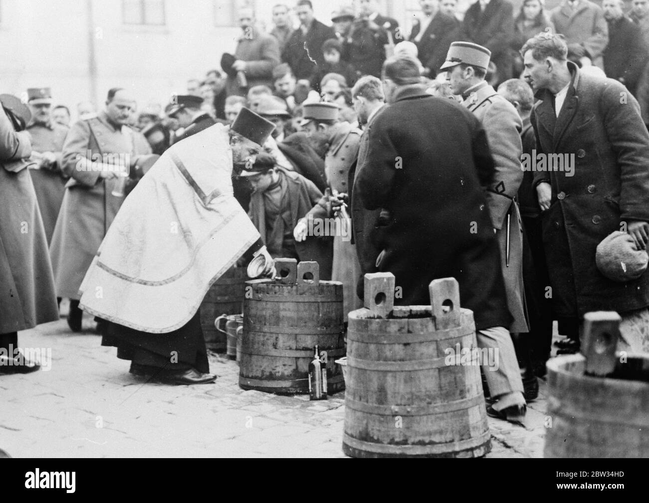 Distributing Holy Water from Sava river at Belgrade . The ancient custom of distributing holy water . The ancient custom of distributing holy water from the River Sava at Belgrade , which the faithful believe has great healing powers . Great crowds attend the ceremony and Gendarmes keep the assembly in order in order . A cross is thrown into the frozen river and the water drawn from the spot where it breaks the ice . The priests distributing the holy water during the ceremony at Belgrade . 23 January 1932 Stock Photo