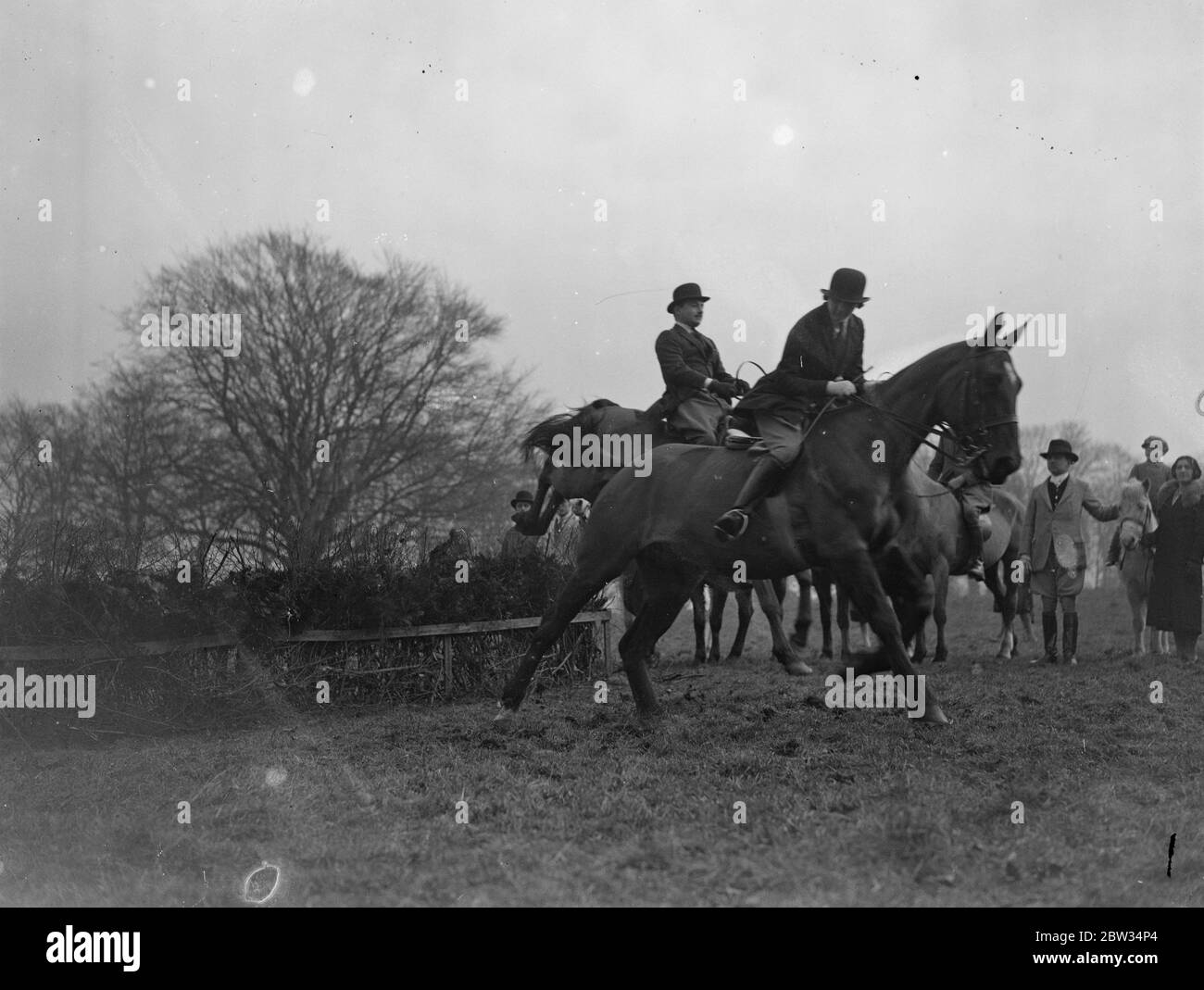 Members of Parliament learn to ride . Members of Parliament are learning to ride a newly formed riding school specially for them at Sanderstead , Surrey . Miss Vera Magee and Mr D B Joel M P taking a jump watched by other members of the school . 3 March 1932 Stock Photo