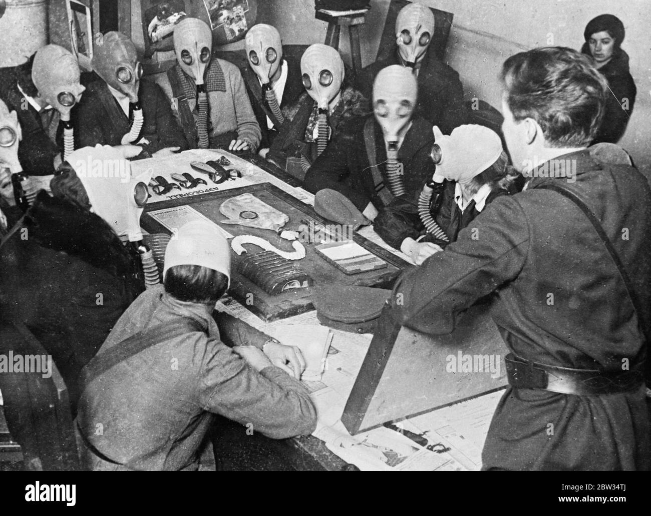 Gas mask drill in Russian factory . Every factory , school and club throughout Russian hold their own military classes , where the general public are taught the uses of guns gasmasks and other war weapons . This is part of the Soviet Governments plan to prepare their citizens in the case of war . Soviet workers at a gas mask instruction class in Moscow . 4 February 1932 Stock Photo