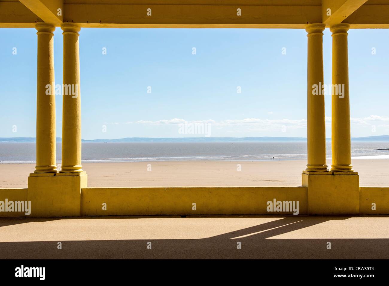 Framed by the eastern shelter on the promenade the beach at Barry Island is almost deserted on a sunny Spring Bank holiday afternoon during the 2020 c Stock Photo
