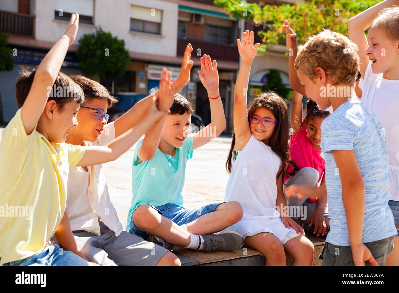Group of positive children holding hands up and smiling together in ...