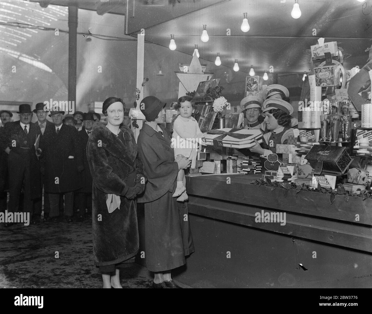 Lady Churchill opens christmas gift stall at Paddington Station . Lady Churchill , wife of Lord Churchill , opened the Christmas gift stall at Paddington Station , London . The roof , girders and pillars of the station have been hung with Christmas decorations and a giant Christmas tree installed . Photo shows ; the Honourable Sarah Churchill with her mother , Lady Churchill , receiving a box of chocolates at the opening of the stall . 15 December 1933 Stock Photo