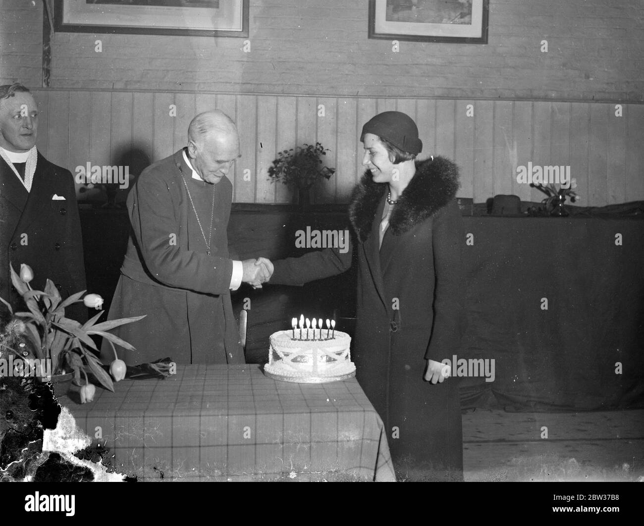 Bishop of London presented with birthday cake . in celebration of his 74th birthday when he conducted the centenary service at the church of ST John the Evangelist at Paddington , London . The presentation was made by Miss Muriel Closier who celebrated her seventeenth birthday the same day . Photo shows , Miss Muriel Closier presenting the birthday cake to the Bishop of London . 27 January 1932 Stock Photo