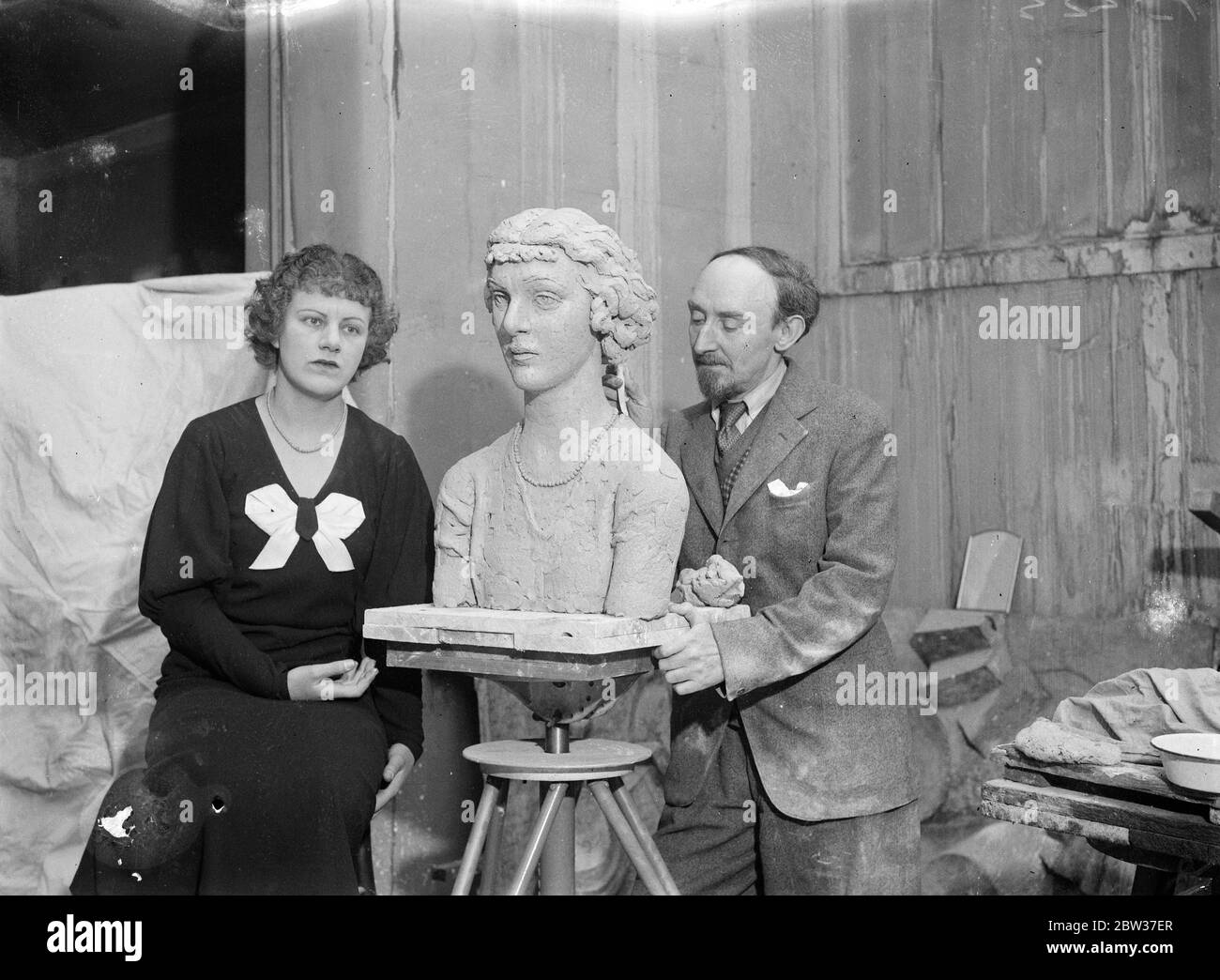 His finest work after six months of idleness . Described by the sculptor as the finest work he has ever done , Mr Frank Dobson is at work on a portrait bust of Miss Peggy Salaman , the famous airwoman , at his London studio . this is the first work Mr Dobson has attempted since he left hospital where for six months he received treatment for a broken shoulder . He is wondering if the enforced idleness has enabled him to surpass his previous artistic efforts . Miss Salaman holds the record for a flight over the Empire route from England to the Cape . Photo shows , Miss Peggy Salaman sitting to M Stock Photo