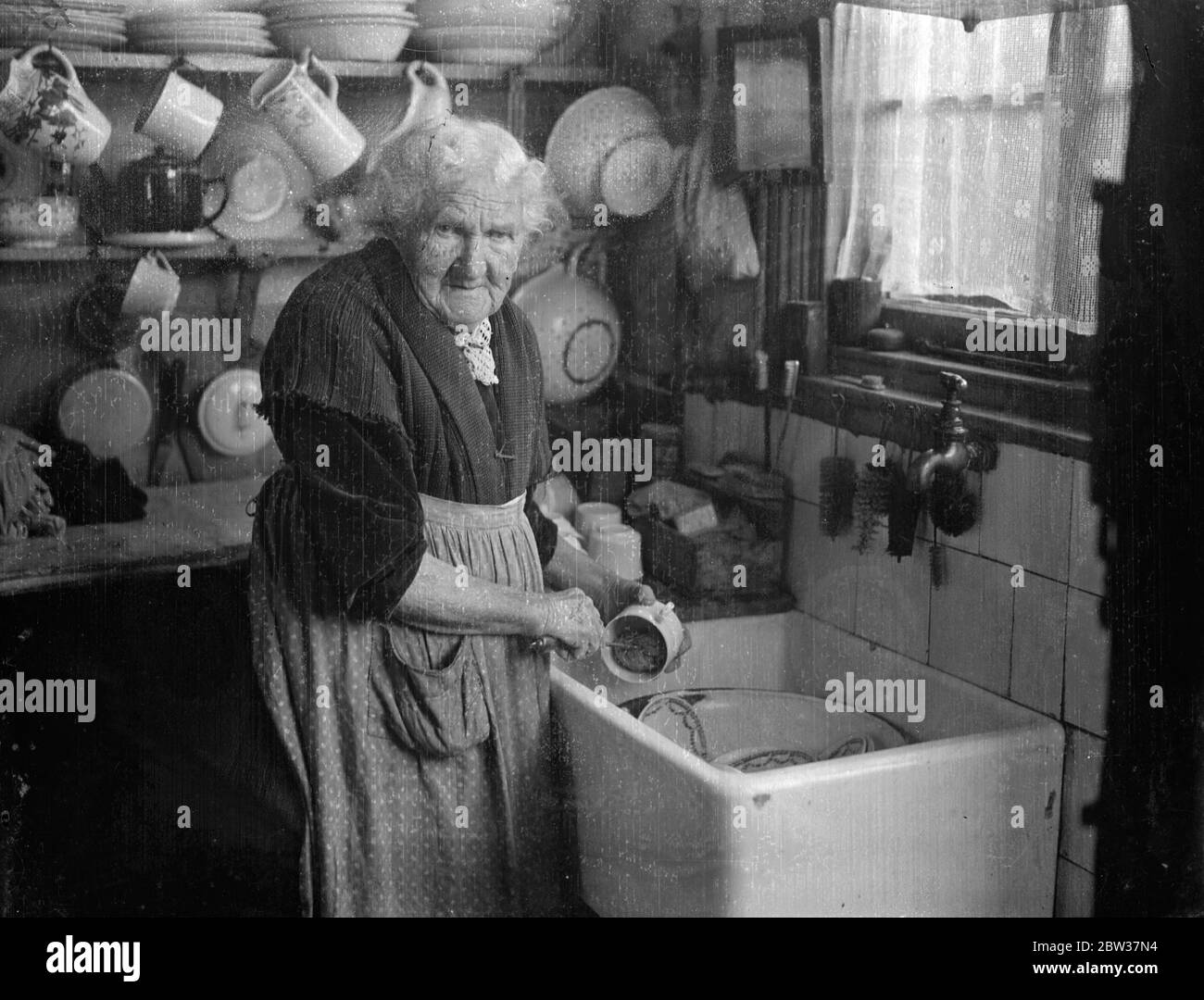 Making Buckinghamshire lace by hand , Mrs Eldridge aged 95 doing the washing up 12 January 1934 Stock Photo