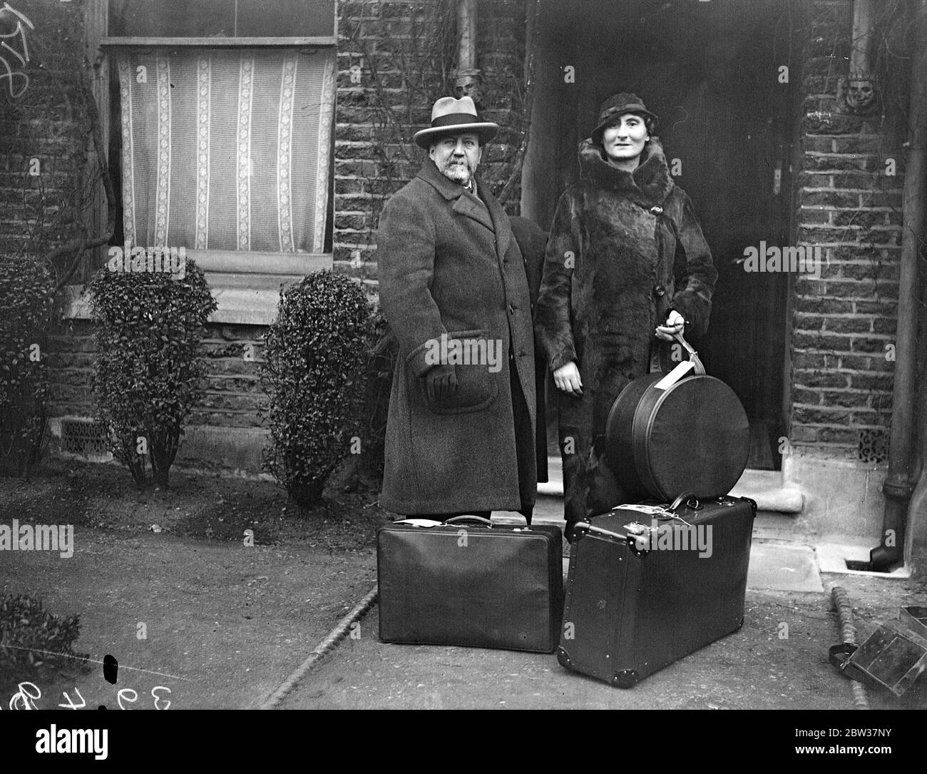 Sir Henry Wood off to Bermuda . Will conduct in America . Sir Henry and Lady Wood left Euston Station , London for Bermuda . From there they will cross to America , where Sir Henry will conduct three concerts at Boston . Photo shows ; Sir Henry and Lady Wood leaving their London home with their luggage . 21 December 1933 Stock Photo