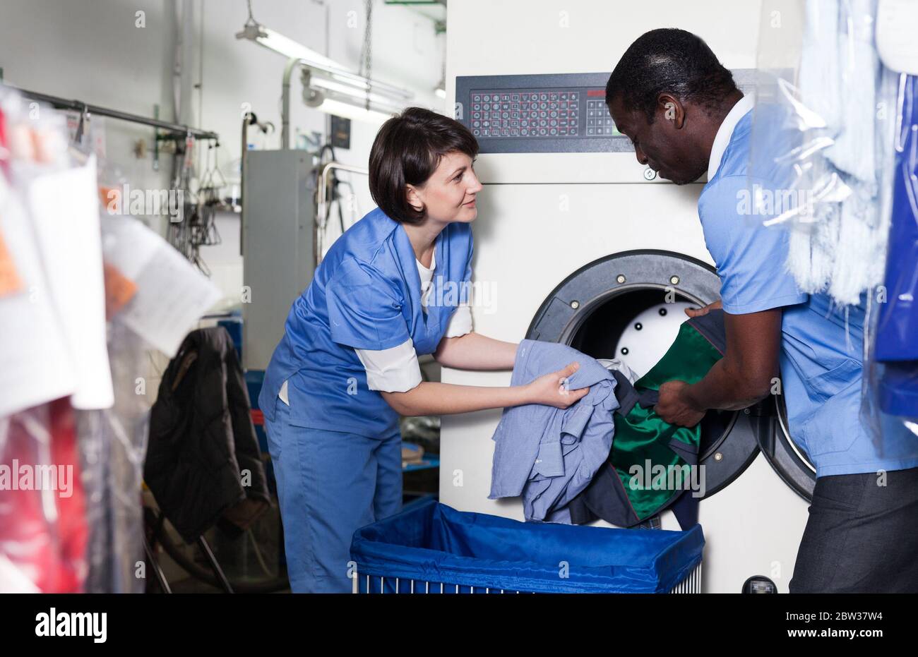Focused African Man With His Female Assistant Sorting Dirty Clothes And focused-african-man-with-his-female-assistant-sorting-dirty-clothes-and