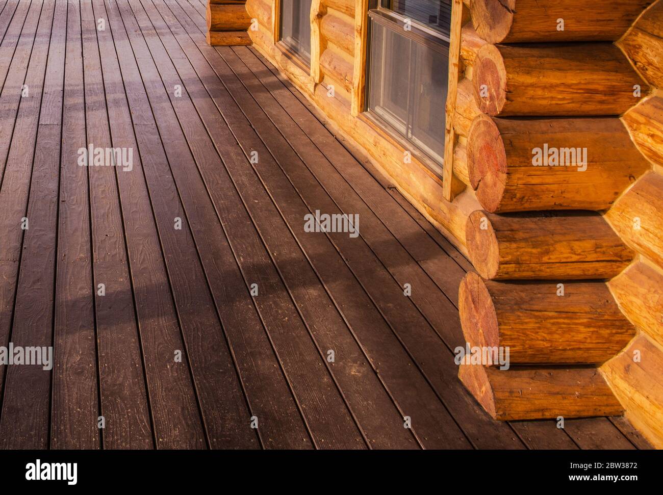 Close Up Photo of Log Home Cabin and Wooden Porch Floor. Wooden Homes Building Theme. Stock Photo
