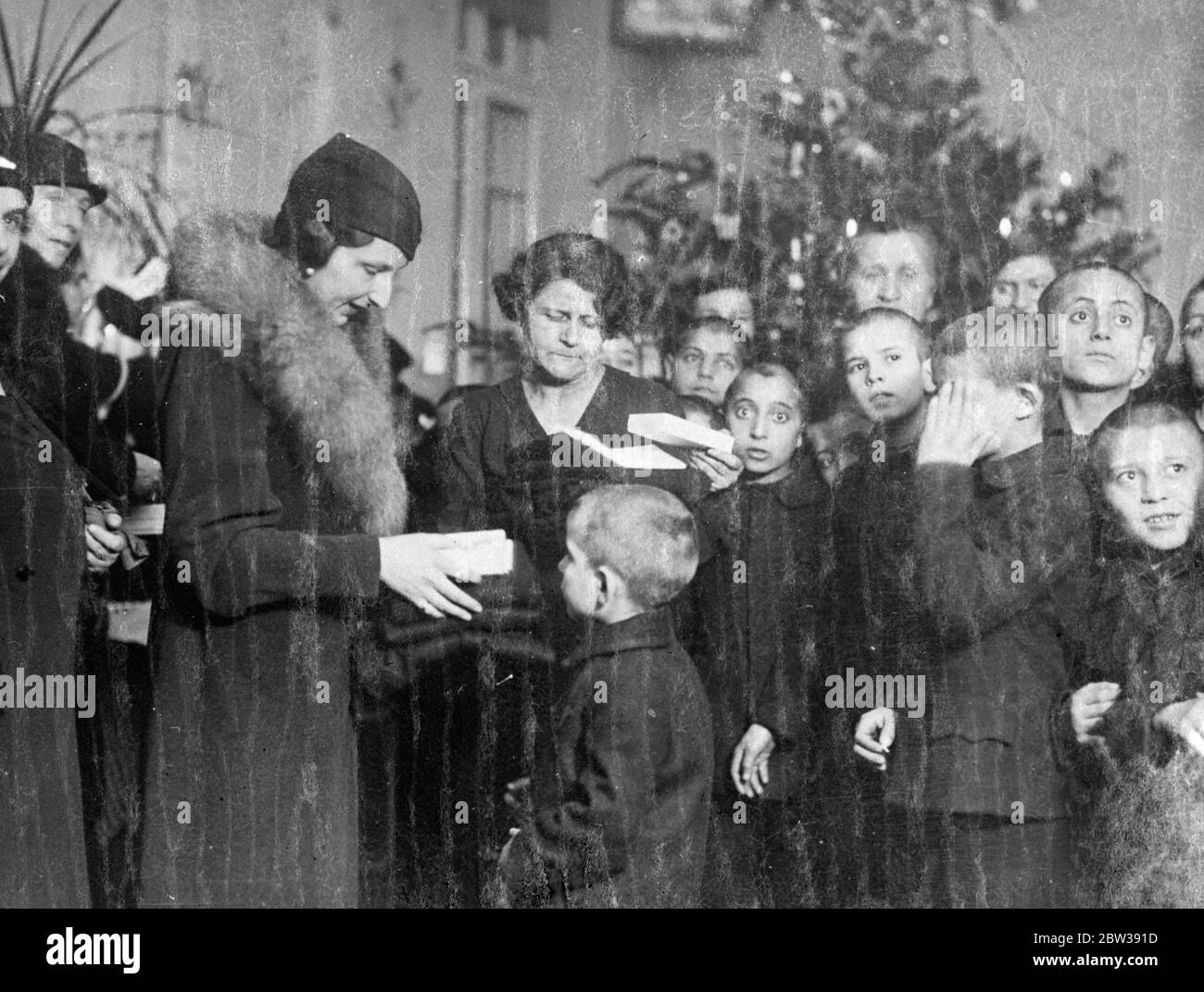 Queen of Bulgaria presents gifts to children . The Queen of Bulgaria paid a visit to an infants hostel and creche in Sofia and distributed gifts to the children . Photo shows ; Queen of Bulgaria distributing gifts to the children during her visit . 15 January 1934 30s, 30's, 1930s, 1930's, thirties, nineteen thirties Stock Photo