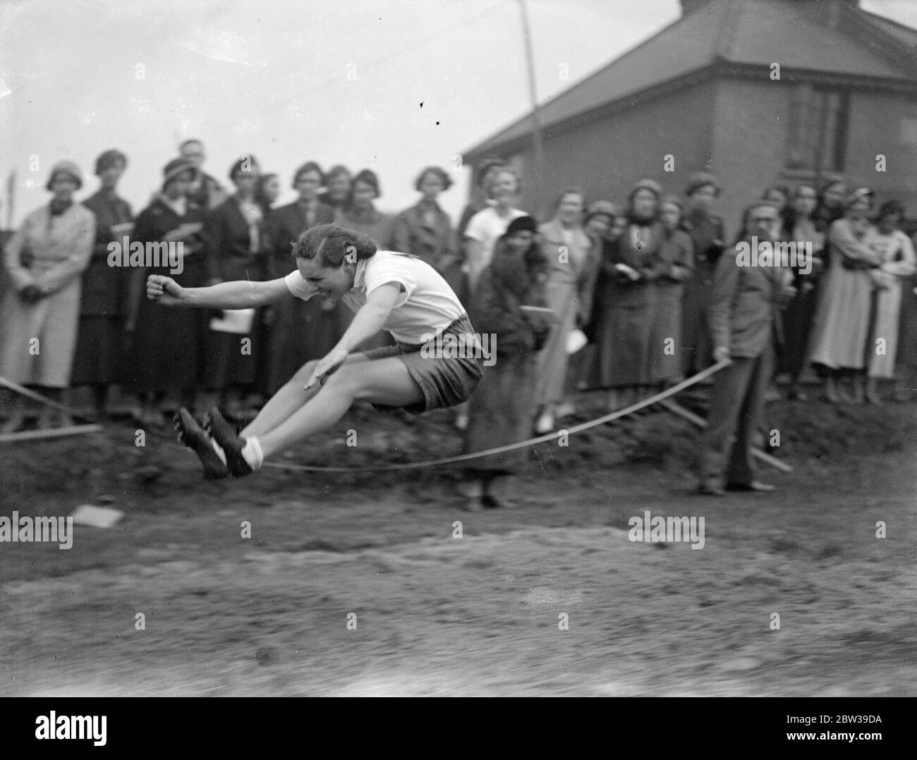 Girl athlete breaks school record for long jump at Kings College sports . Miss Barbara Eve broke the school record for the long jump , when she jumped 16 feet four inches and won the event at the King ' s College , sixty - second annual Athletic meeting , held at the College War Memorial Grounds , Lavenden Avenue , Mitcham . Photo shows ; Miss Barbara Eve breaking the record for the school with a long jump of 16 feet 4 inches . 28 April 1934 Stock Photo