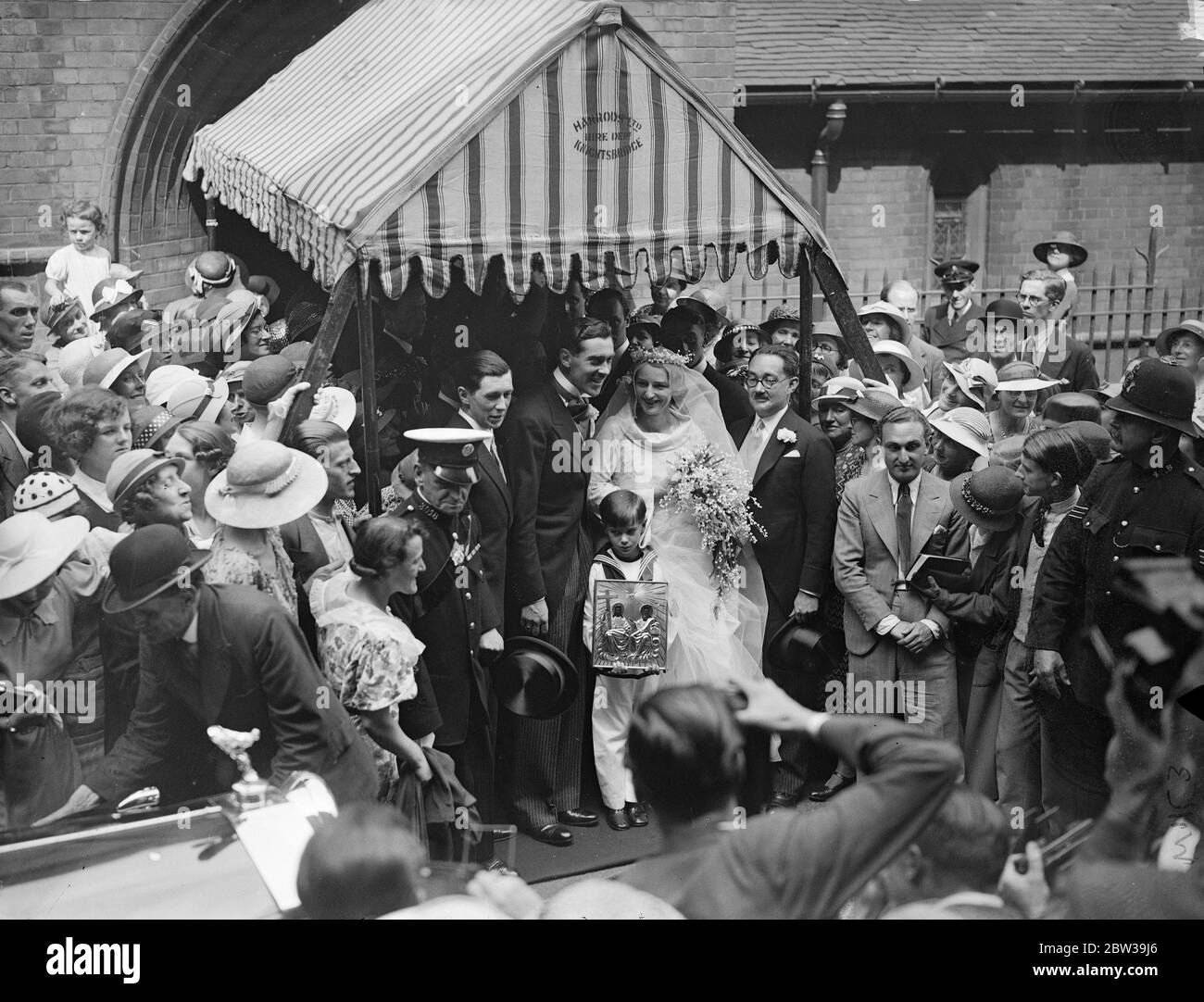 Sailor page boy at Russian orthodox wedding of Lord Howard De Walden ' s daughter and Count Serge Orloff Davidoff , at the Russian Orthodox Church , St Philip ' s , Buckingham Palace Road . Photo shows , the page boy with his symbol , leaving the church with the bride and groom . 24 July 1935 Stock Photo