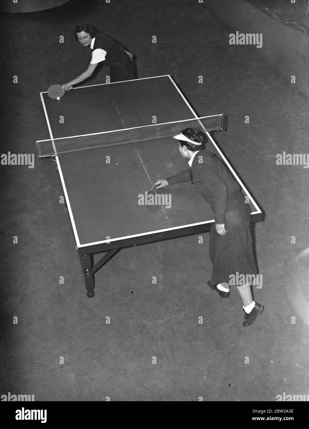 German women players in action at table tennis championships at the Imperial Institute , Kensington . A overhead view of two German players in action - further from camera is Frau Krebabech , and nearer camera is Fraulein Bussmann . 9 February 1935 Stock Photo