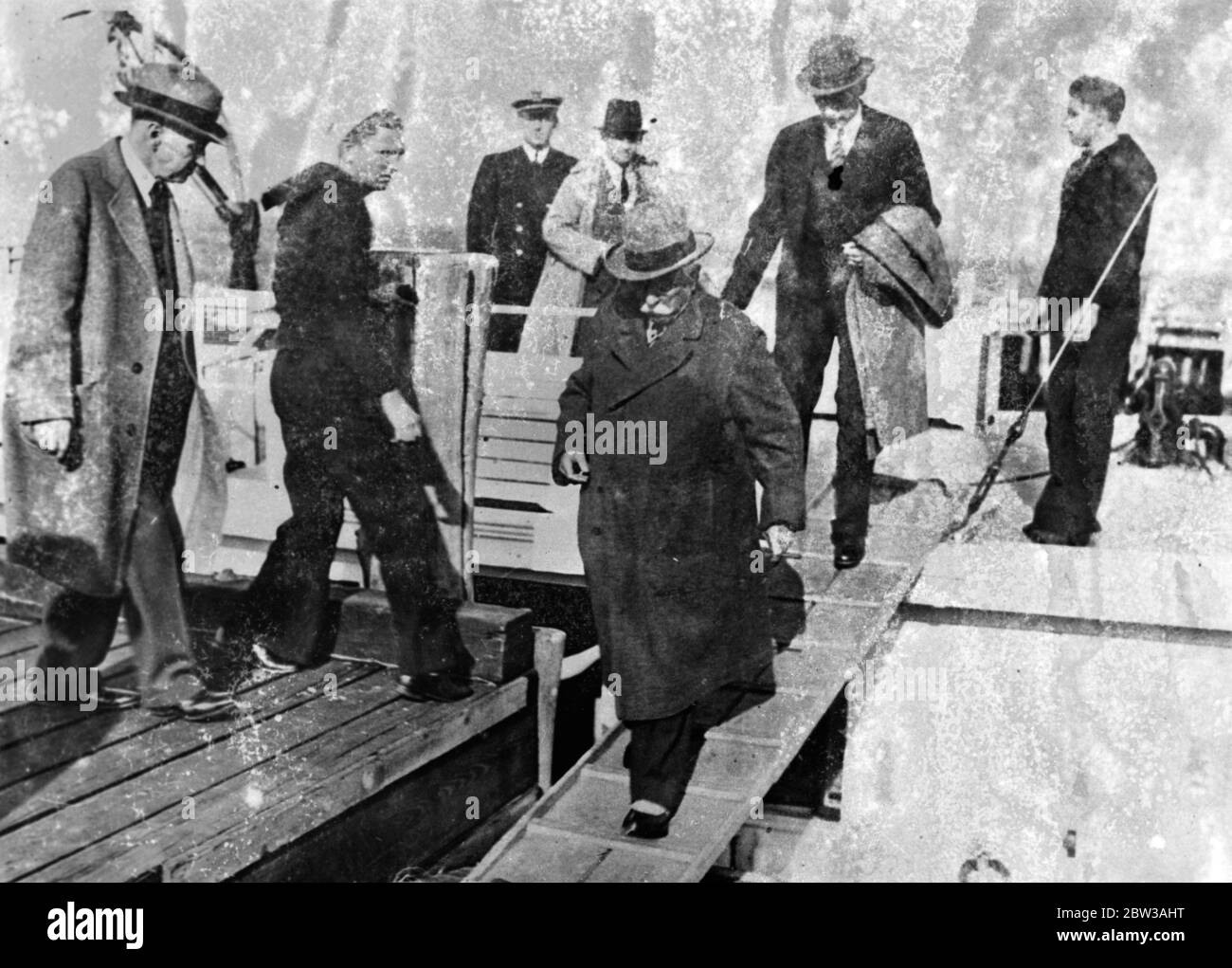 Samuel Insull , former utilities magnate , is pictured leaving the Coast Guard cutter USS Hudson , to which he was transferred upon his arrival in New York harbour , May 7 aboard the SS Exilona . On his left is Burton Y Berry US embassy attache in Istanbul , under whose custody Insull made the trip to the United States . The cutter brought Insull to Fort Hancock , where he was placed in an automobile , taken to a railroad station and put aboard a train for Chicago , where he will placed on trial for embezzlement . 7 May 1934 Stock Photo