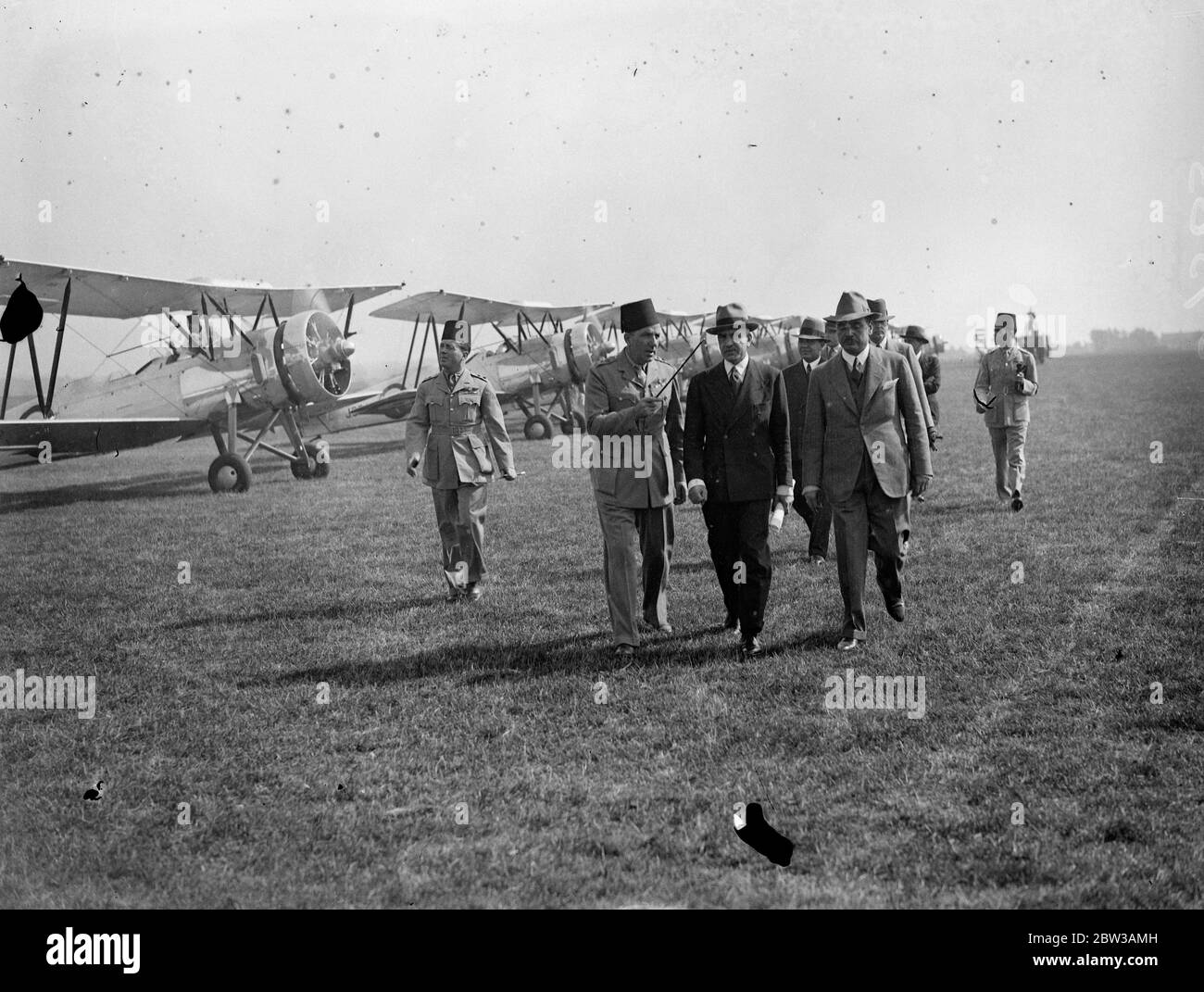 Egyptian air squadron tested at Lympne before formation flight to Egypt . To be used to suppress dope smuggling . A fleet of ten Avro biplanes built in England for the Egyptian Government underwent tests and official inspection at Lympne Aerodrome , Kent , before taking off for a formation flight to Cairo . The planes will be used in Egypt for military purposes and in suppressing the drug traffic . Photo shows the Egyptian Charge d' Affaires in London , H E Hakki Bey , inspecting the squadron and Egyptian officers at Lympne . 14 September 1934 Stock Photo