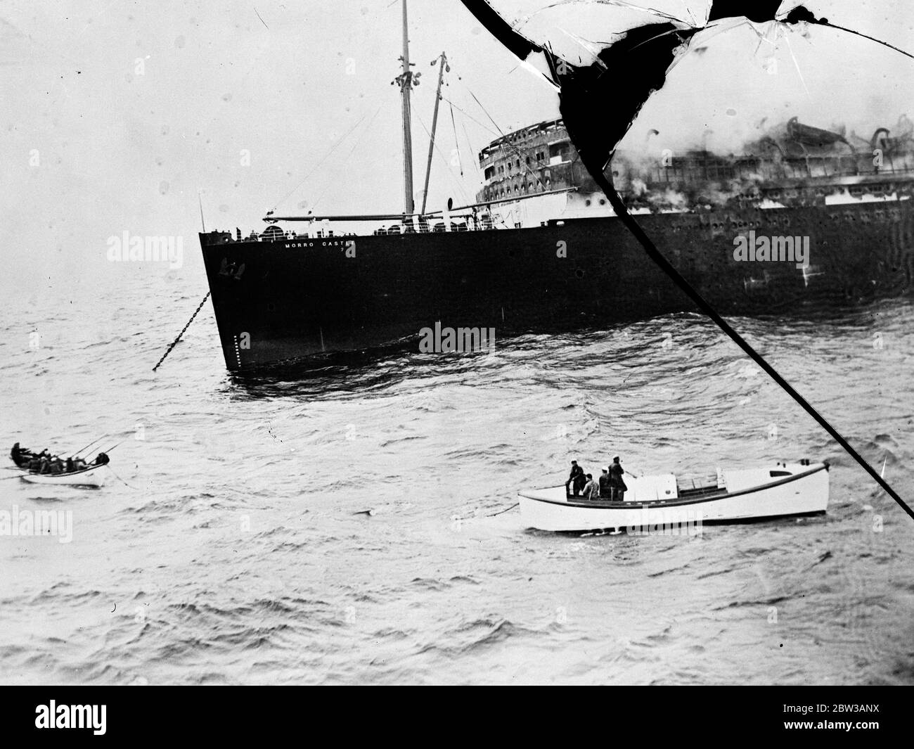 These are the first original pictures to reach London of the disaster to the American cruise liner SS Morro Castle in which nearly two hundred people lost their lives . the ship was destroyed by fire off the coast from Havana . The cause of the catastrophe , one of the greatest in maritime history , is still a mystery , but evidence given before the commission of enquiry in New York indicated that the fire was started by incenderies . While an inferno rages aboard the doomed Morro Castle a tiny boat load of survivors pulls out from under the looming hulk of the ill fated vessel . Others less f Stock Photo