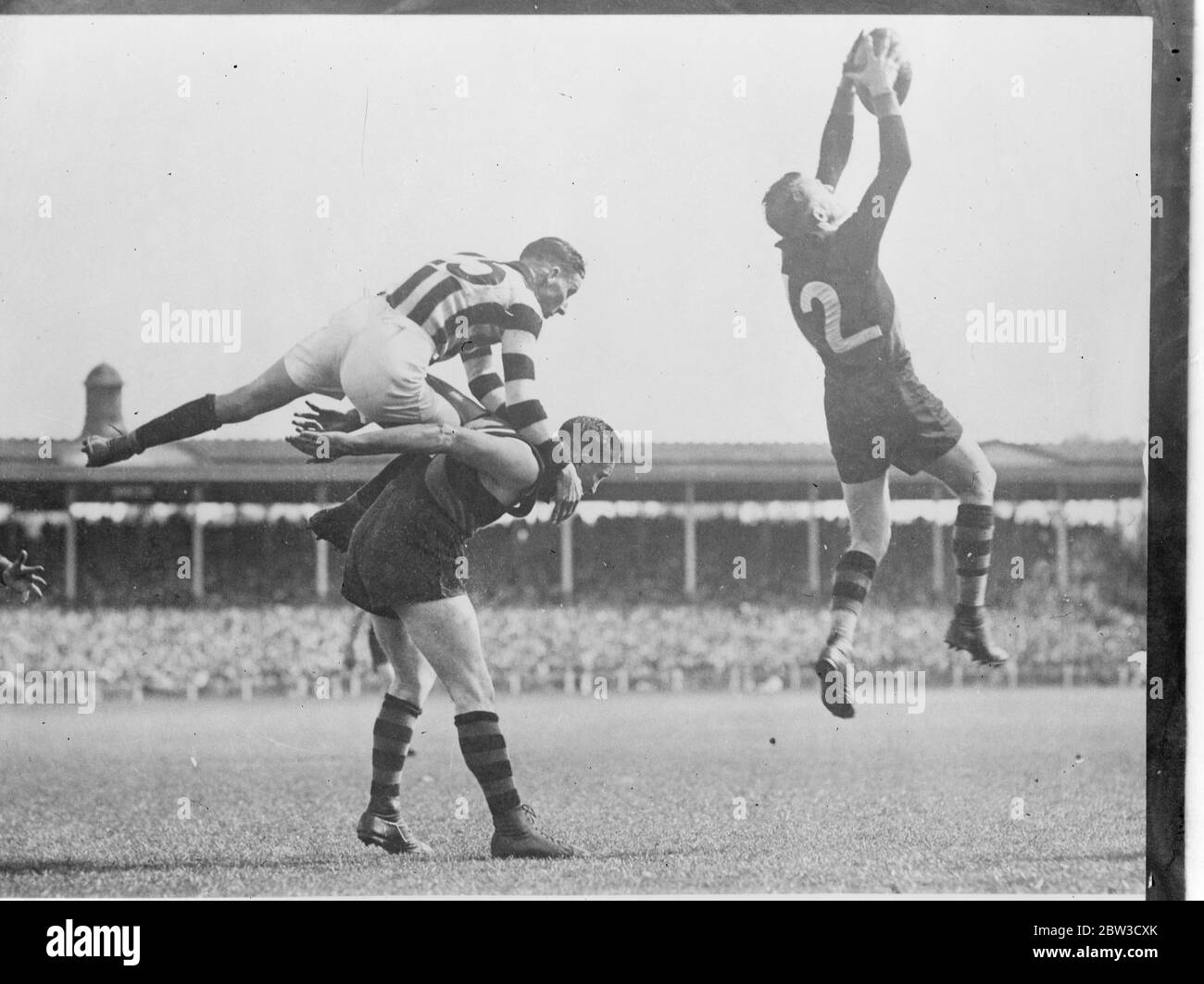 Regan , full back of the Collingwood Rugby team , makes a spectacular leap onto the back of Bentley ( Richmond ) in the League football semi final at Melbourne , Victoria . Titus , the Richmond player on right , was able to mark , and a goal followed . 3 November 1935 Stock Photo