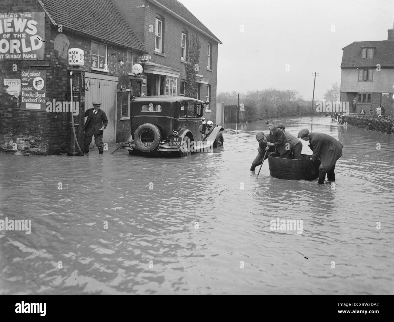 Where the bath tub beats the motorcars . Floods in Kent . A car filling up with petrol in flooded Yalding , Kent . The tub on right seems a more satisfactory means of transport under the circumstances . 18 November 1935 Stock Photo