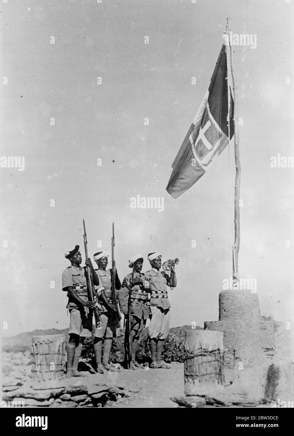 Tri colour flies over conquered territory . Photo shows , the Italian tricolour fluttering from an improvised mast as a native bugler sounds his call in newly conquered territory in northern Abyssinia . 10 November 1935 Stock Photo