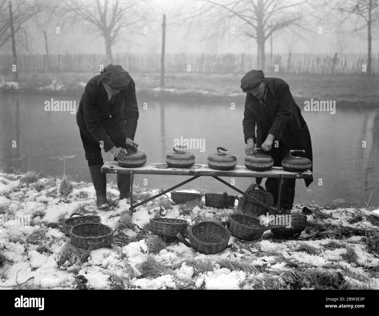 Cold snap brings curling prospects to London . Following the coldest night of the year when 13 degrees of frost was recorded , curlers gathered optimistically at Wimbledon Common in the hope that the rink there would have a coating of ice thick enough to permit play . Photo shows , cleaning the curling stones ready for action at Wimbleon Common . 29 January 1935 Stock Photo