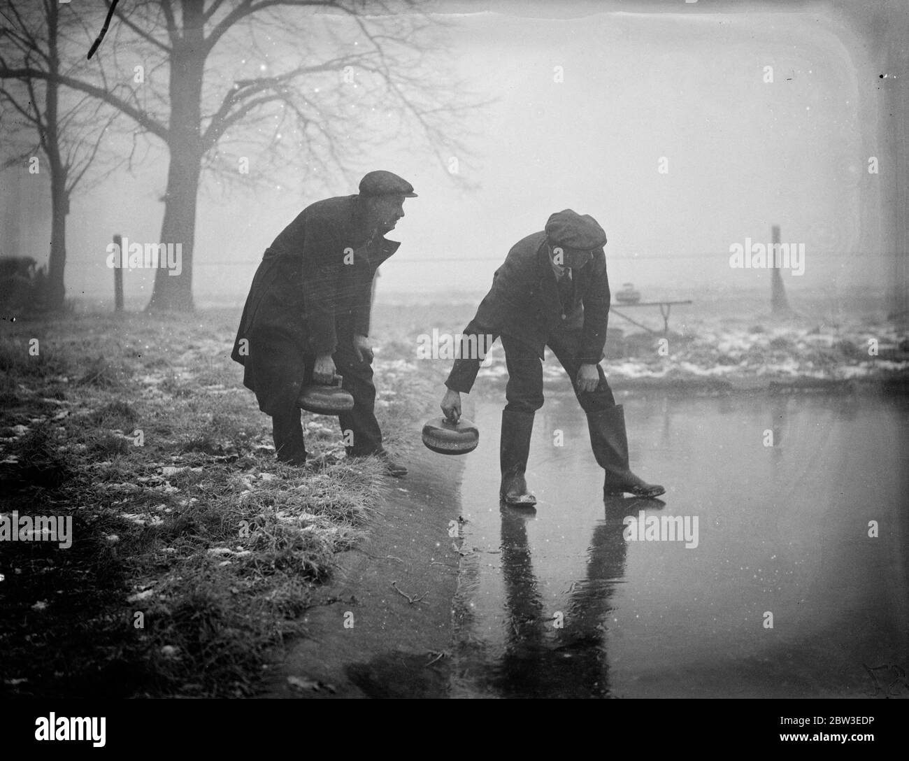 Cold snap brings curling prospects to London . Following the coldest night of the year when 13 degrees of frost was recorded , curlers gathered optimistically at Wombledon Common in the hope that the rink there would have a coatin of ice thick enough to permit play . Photo shows , testing the curling stones for action at Wimbleon Common . 29 January 1935 Stock Photo