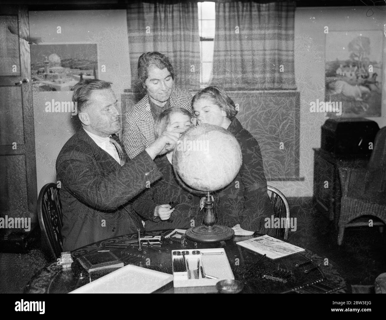 Englishman to count the votes of the Saar Plebiscite . Mr Ben Greene has been appointed Deputy Chief Returning Officer for the Saar Plebiscite . Photo shows ; Mr Ben Greene showing his family where the Saar region is on a globe. 30 December 1934 Stock Photo