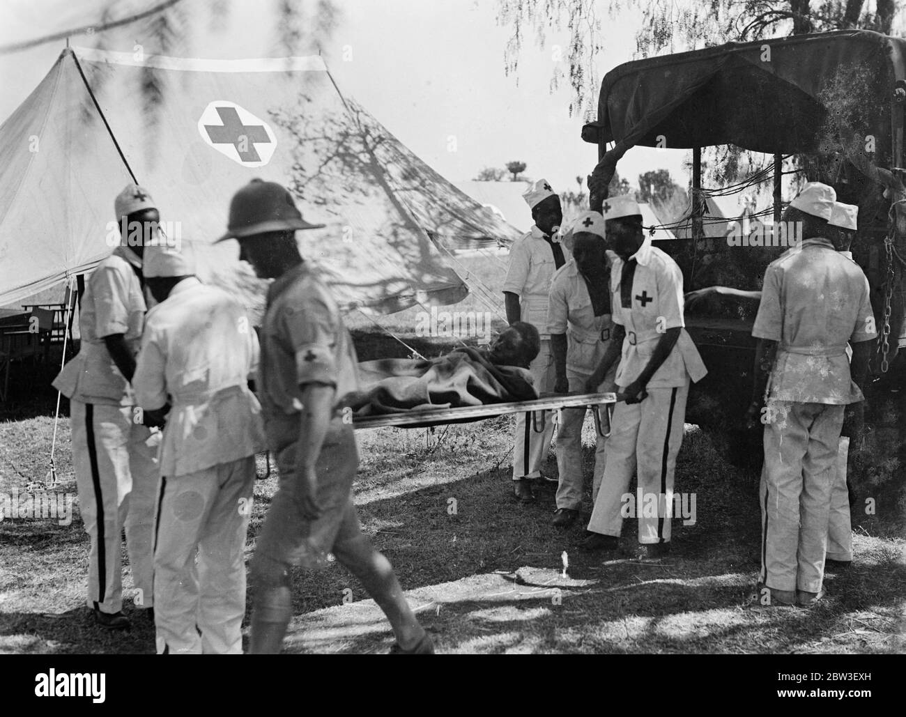 Casulties arrive at a British Field hospital . Abyssinians wounded in the fighting on the southern front arriving on stretchers at a British Red Cross field hospital near Harar . A fleet of motor ambulances is kept busy patrolling the battle zone for casulties . The doctors of the British Red Cross stations are assisted by natives from Kenya , British Somaliland and other British territories . 29 December 1935 Stock Photo