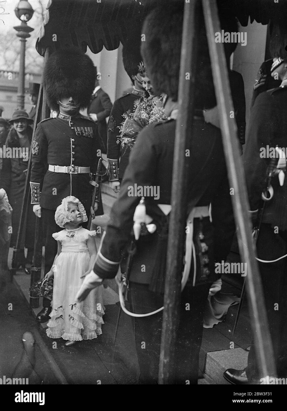 Fellow guests at a London wedding ! . The wedding of Mr Gerald E W Potter , Grenadier Guards and Miss Virginia Stuart Reynolds took place at the Royal Military Chapel , Wellington Barracks . Photo shows a tiny bridesmaid gazing upwards at a tall member of the guard of honour . 5 March 1936 Stock Photo
