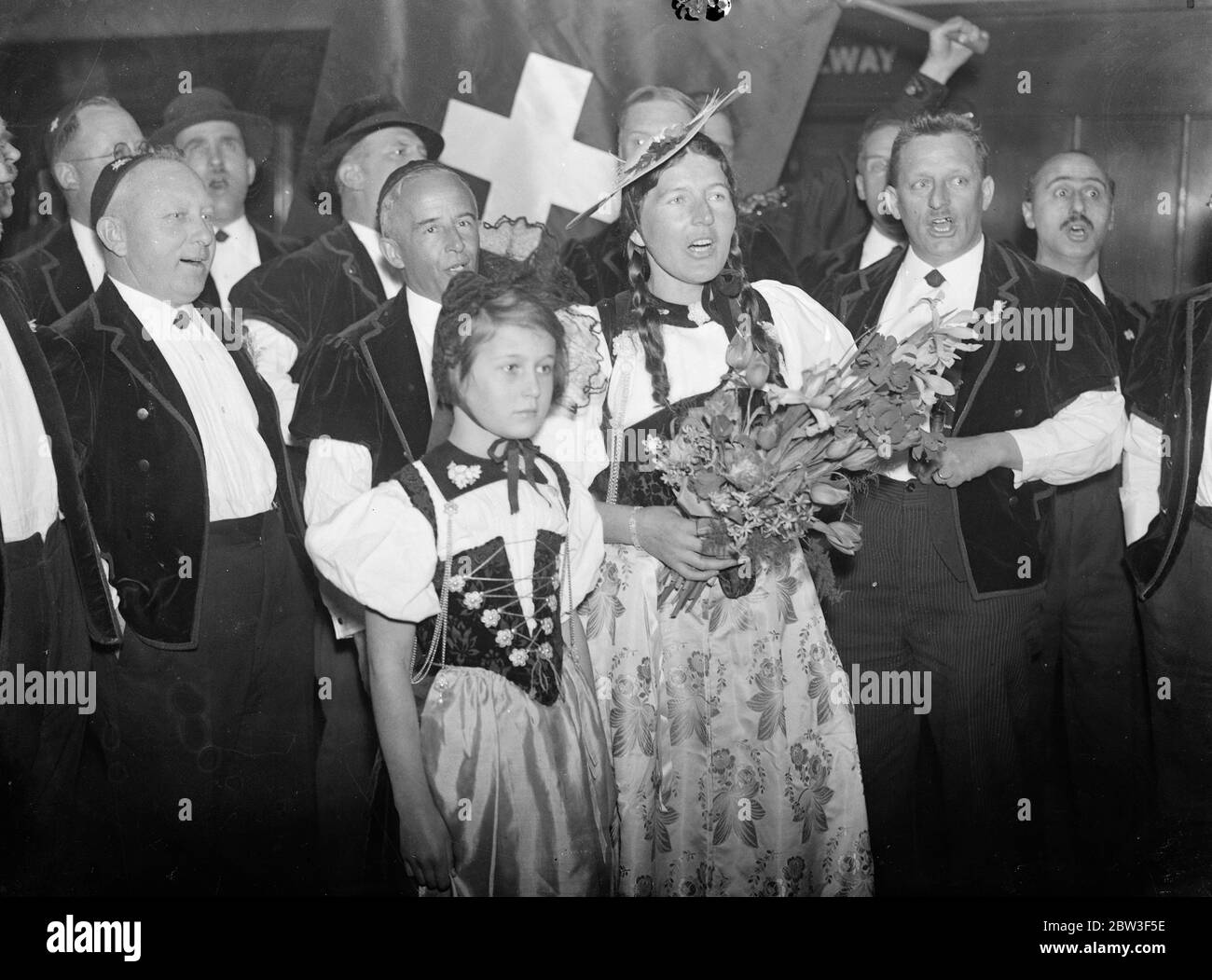 Swiss yodellers arrive in London . To sing at Albert Hall . A party of Swiss Yodellers , dressed in national costume arrived at Victoria STation to sing at the Royal Albert Hall tomorrow ( Saturday ) . They were welcomed by Mr C B Paravicini , the Swiss Minister in London . There were 16 members . Photo shows , members of the choir singing at Victoria on arrival . 6 March 1936 Stock Photo