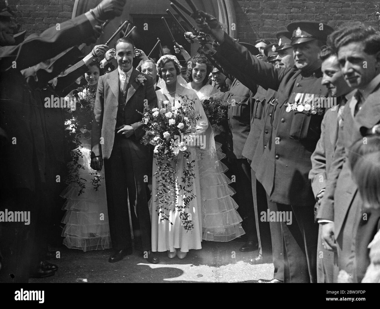 Uncaptioned Wedding - married couple make their way out of church under a guard of honour Stock Photo