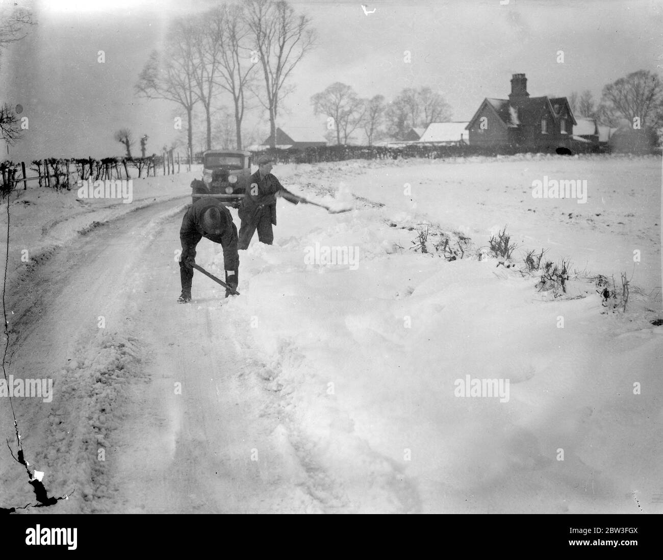 Snowdrifts hold up traffic in Hertfordshire . Photo shows ; Men clearing the roads of snow . 27 January 1935 Stock Photo