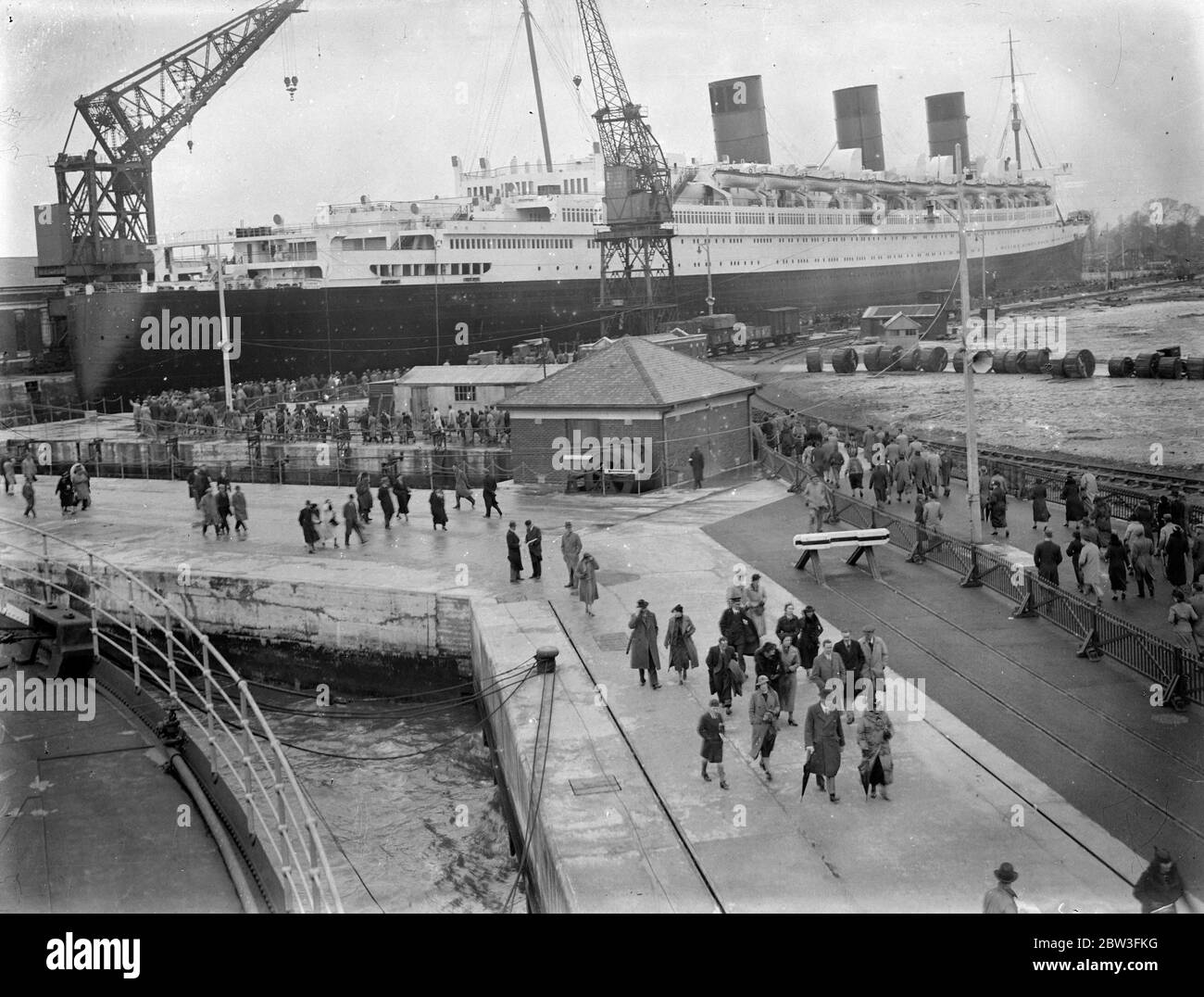 Thousands inspects the Queen Mary in dry dock at Southampton . Dwarfed